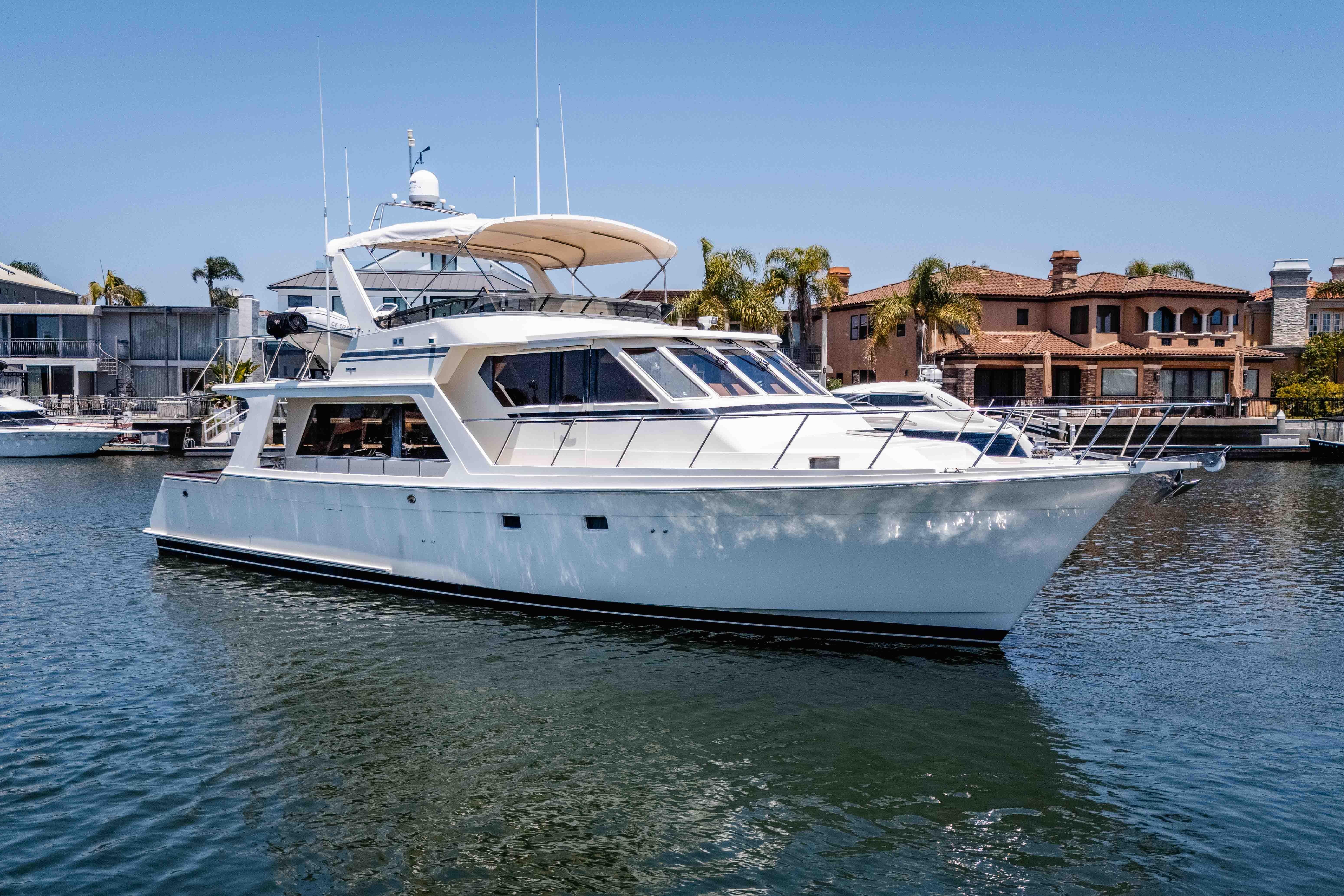 2005 Offshore Yachts 54 Pilothouse cruising in a marina with waterfront homes.