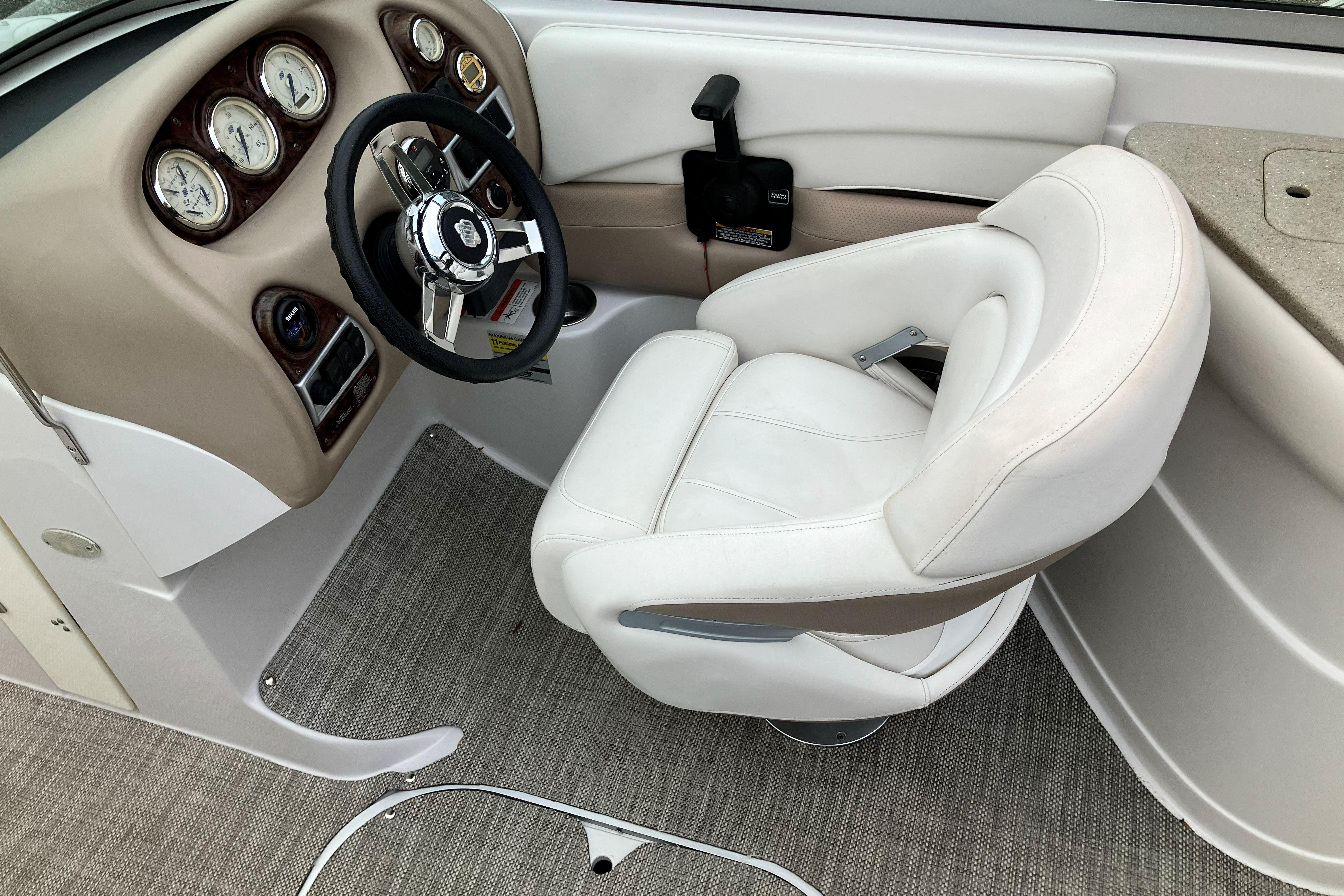 2006 Four Winns 240 Horizon boat cockpit with steering wheel and white captain's chair.