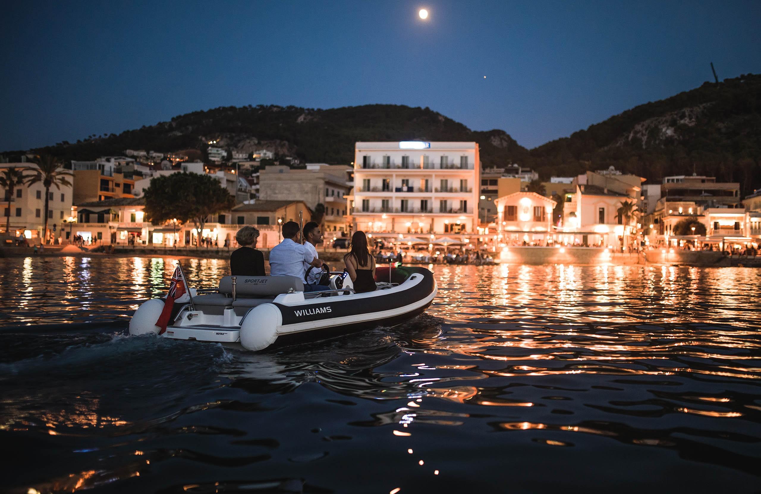 2025 Williams Jet Tenders Sportjet 435 cruising at night near illuminated coastal town.