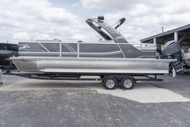 2026 SunCatcher Elite 326 SS pontoon boat on trailer, side view, under cloudy sky.