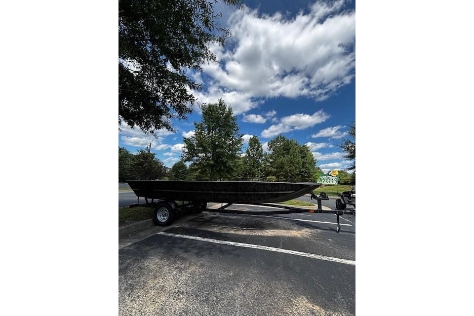 2026 Tracker Grizzly 1860 Utility boat on trailer under a partly cloudy sky.