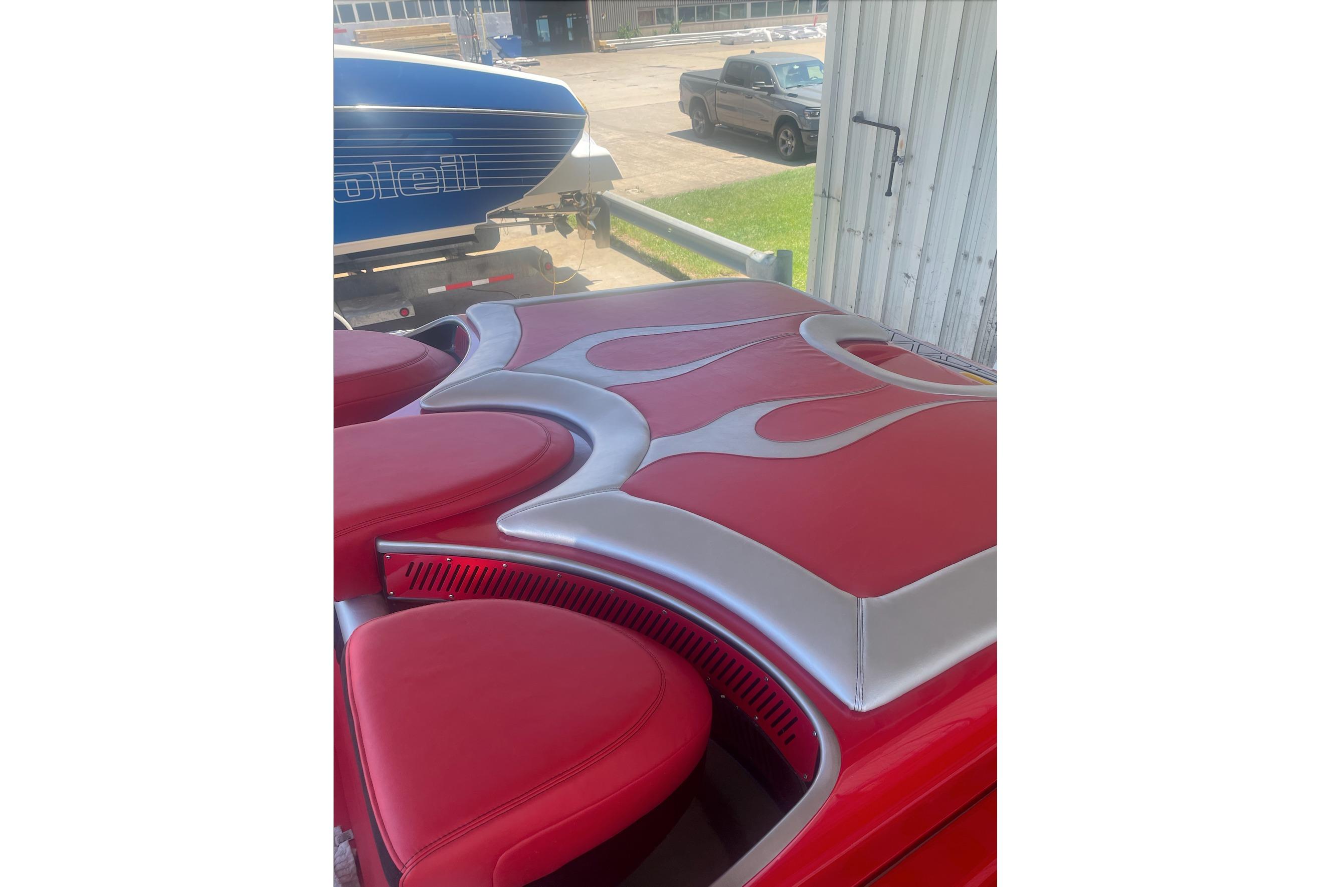 Red and silver interior of a 2005 Hustler 388 SLINGSHOT boat with flame design.