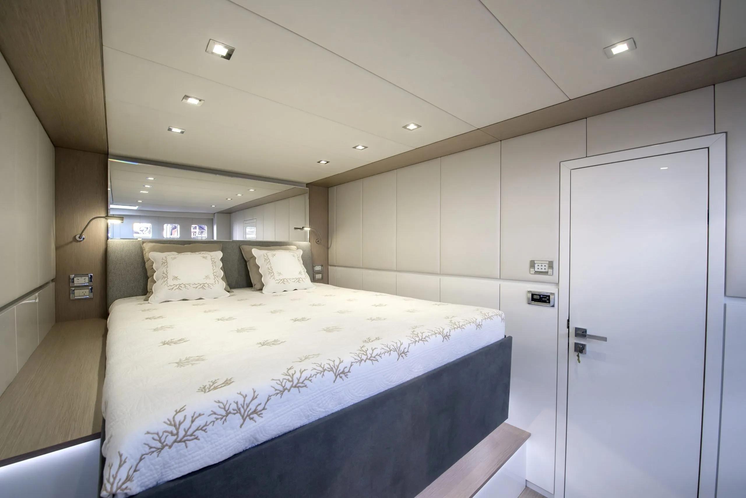 Luxurious bedroom interior of 2016 Sunreef 70 Power yacht with modern design and elegant bedding.