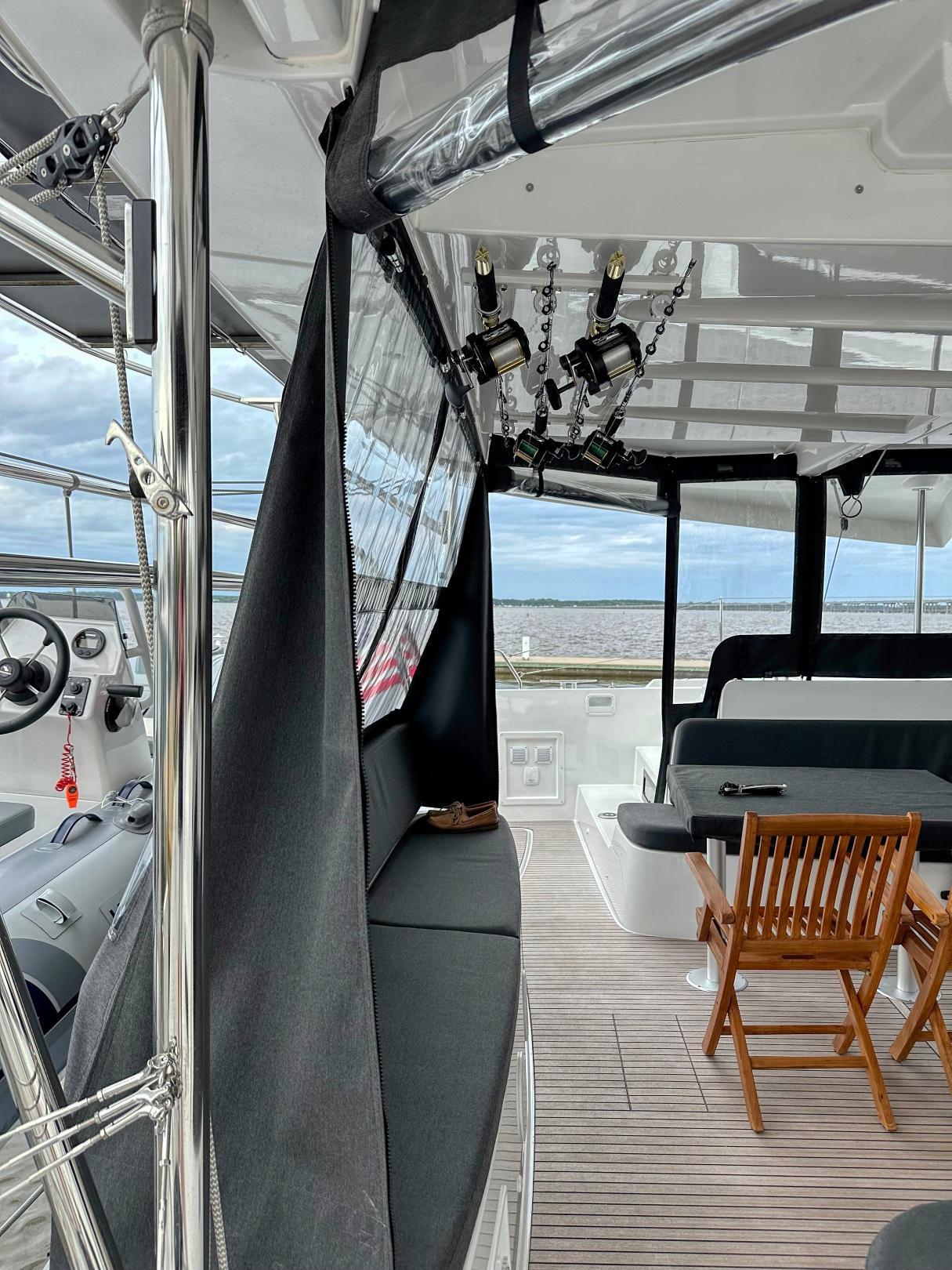 2024 Lagoon 46 yacht interior with seating, wooden chair, and ocean view.
