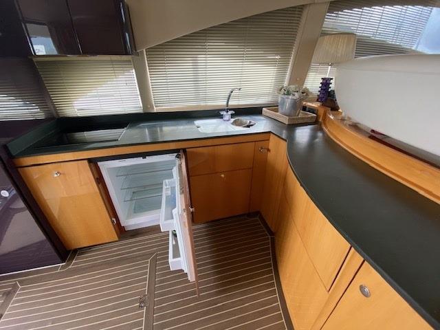 2005 Sealine T60 yacht kitchen with open fridge, wooden cabinets, and sleek countertops.