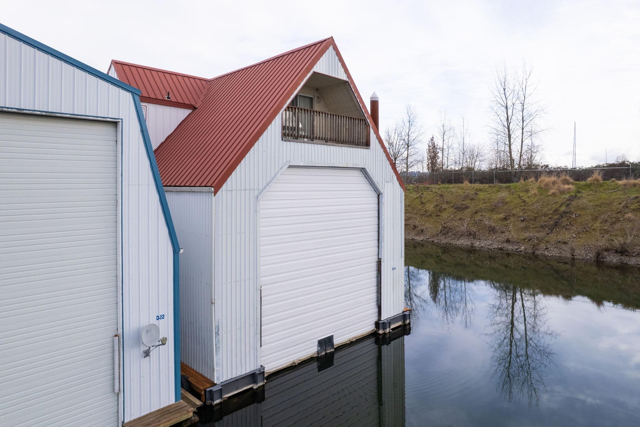Custom 1976 boathouse with red roof, white siding, and water reflection.