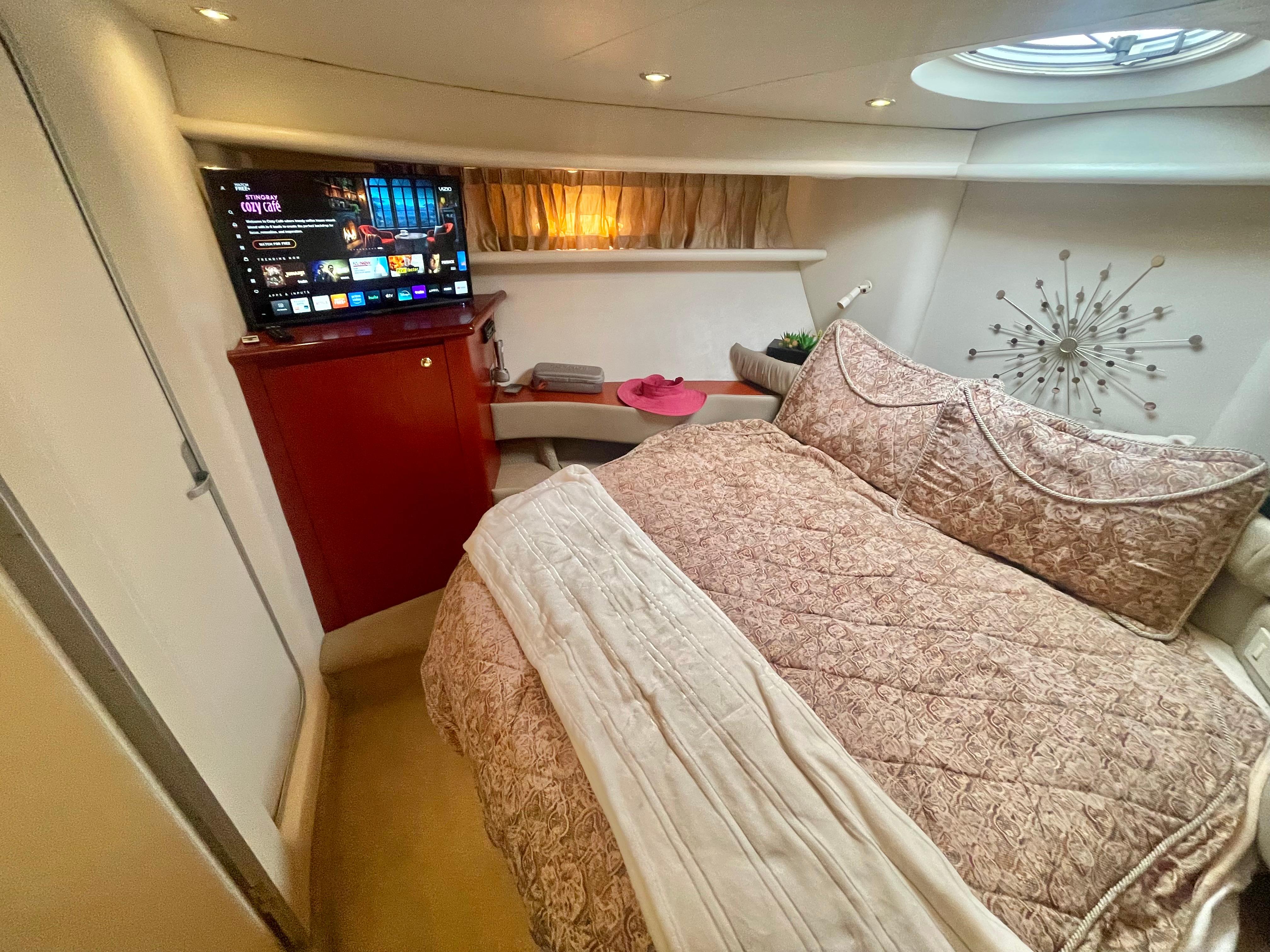 Luxurious bedroom in a 1998 Maxum 4100 SCA yacht with TV and elegant decor.