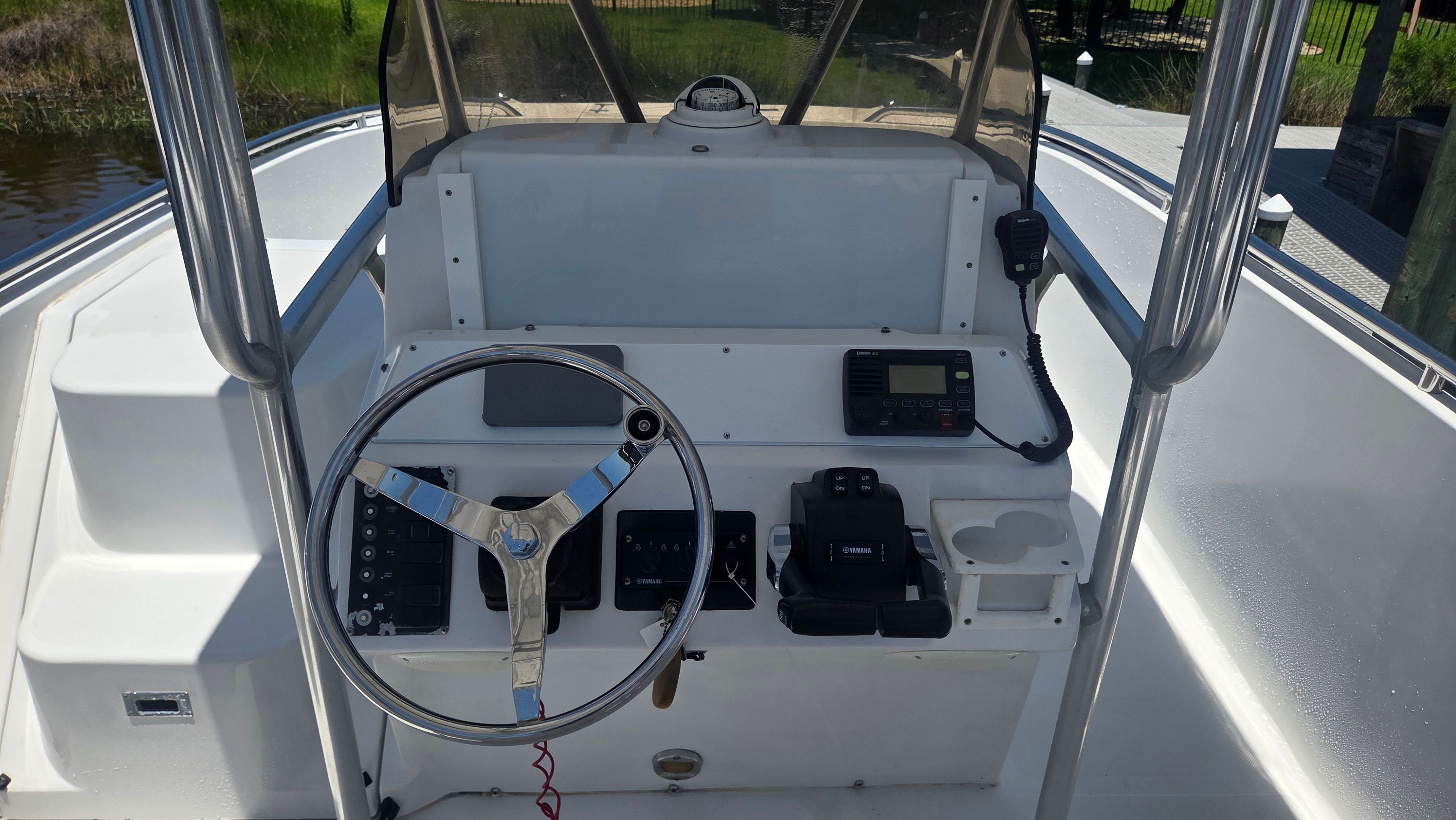 The image shows a boat's helm with a steering wheel, instruments, and a radio.
