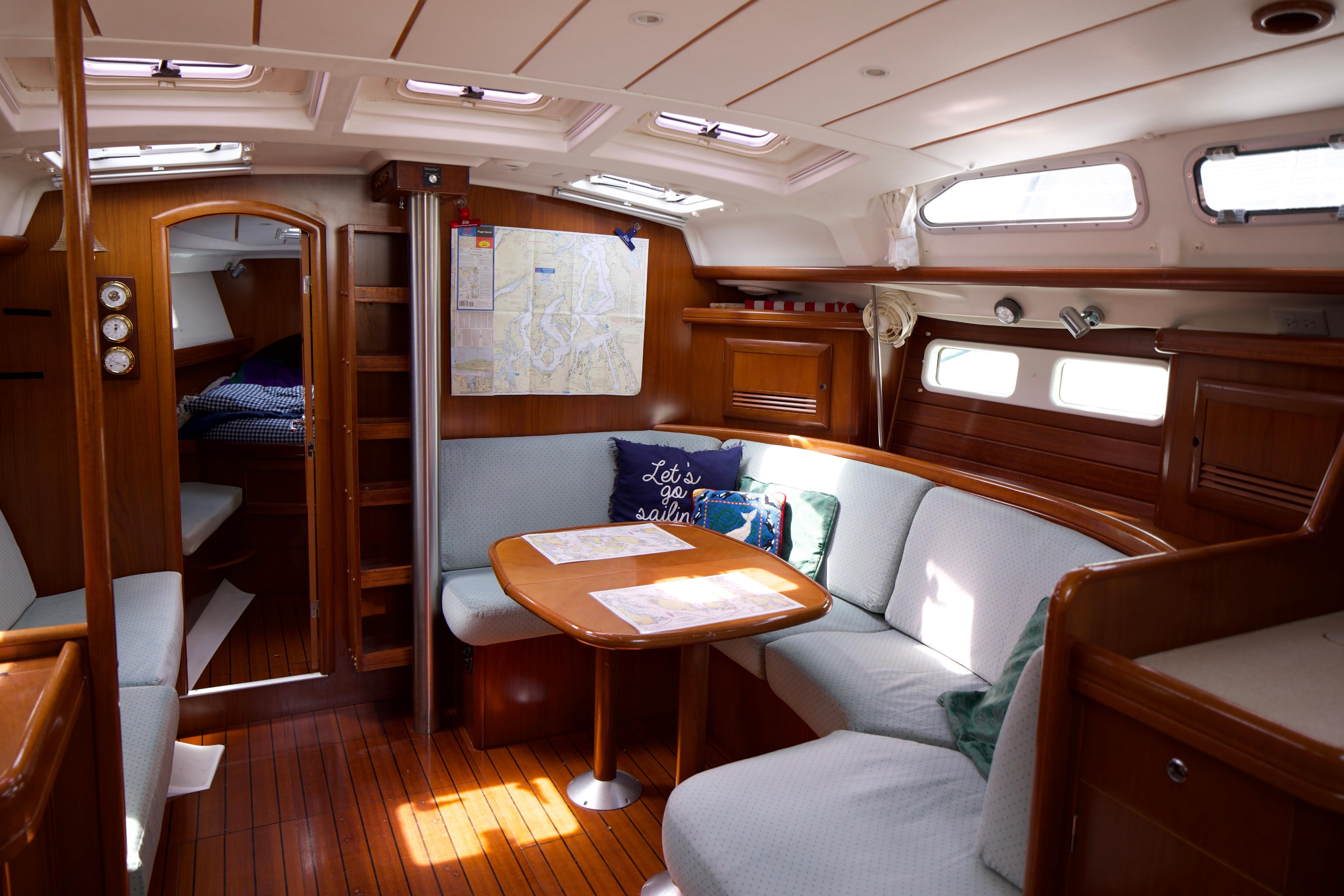 Interior of a 2005 Beneteau 423 sailboat with cozy seating and wooden finishes.
