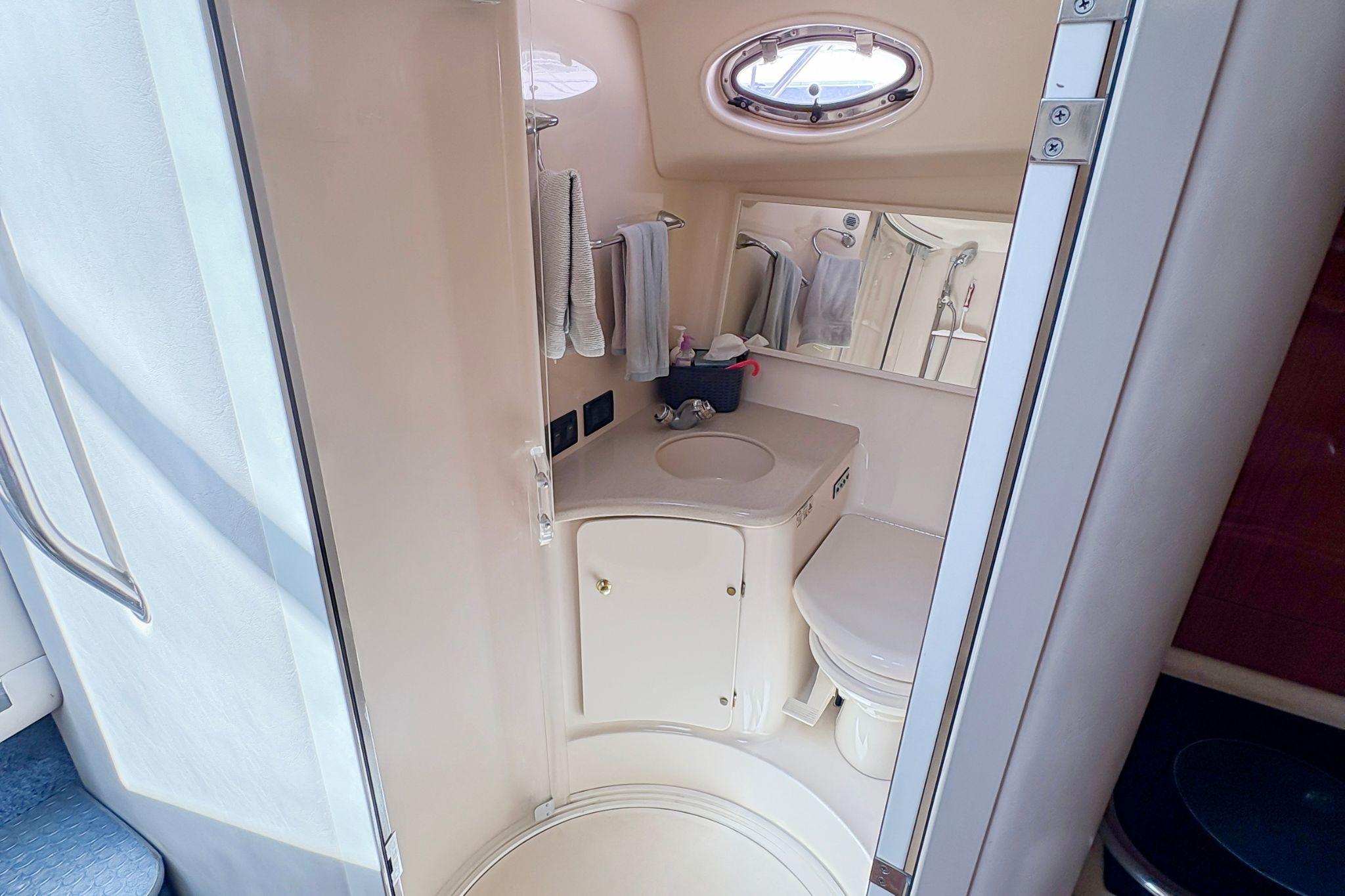 1997 Sea Ray 370 Express Cruiser bathroom with sink, toilet, and mirror.