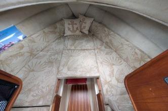 V berth cabin interior with patterned cushions and wooden accents.