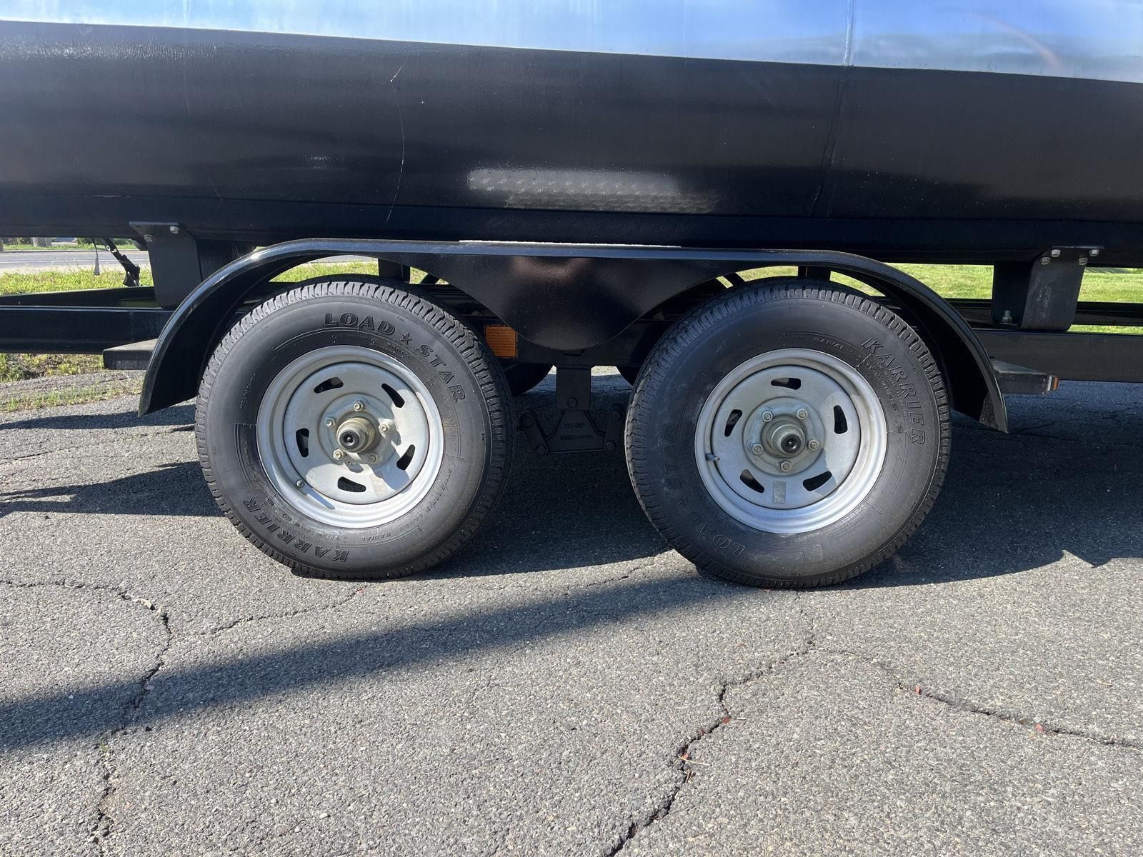 A boat trailer with two large tires on a paved surface.