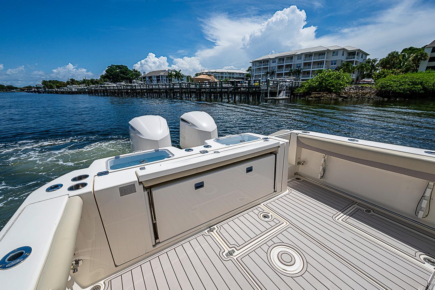 2019 Cobia 320 Center Console boat on calm waters near a dock.