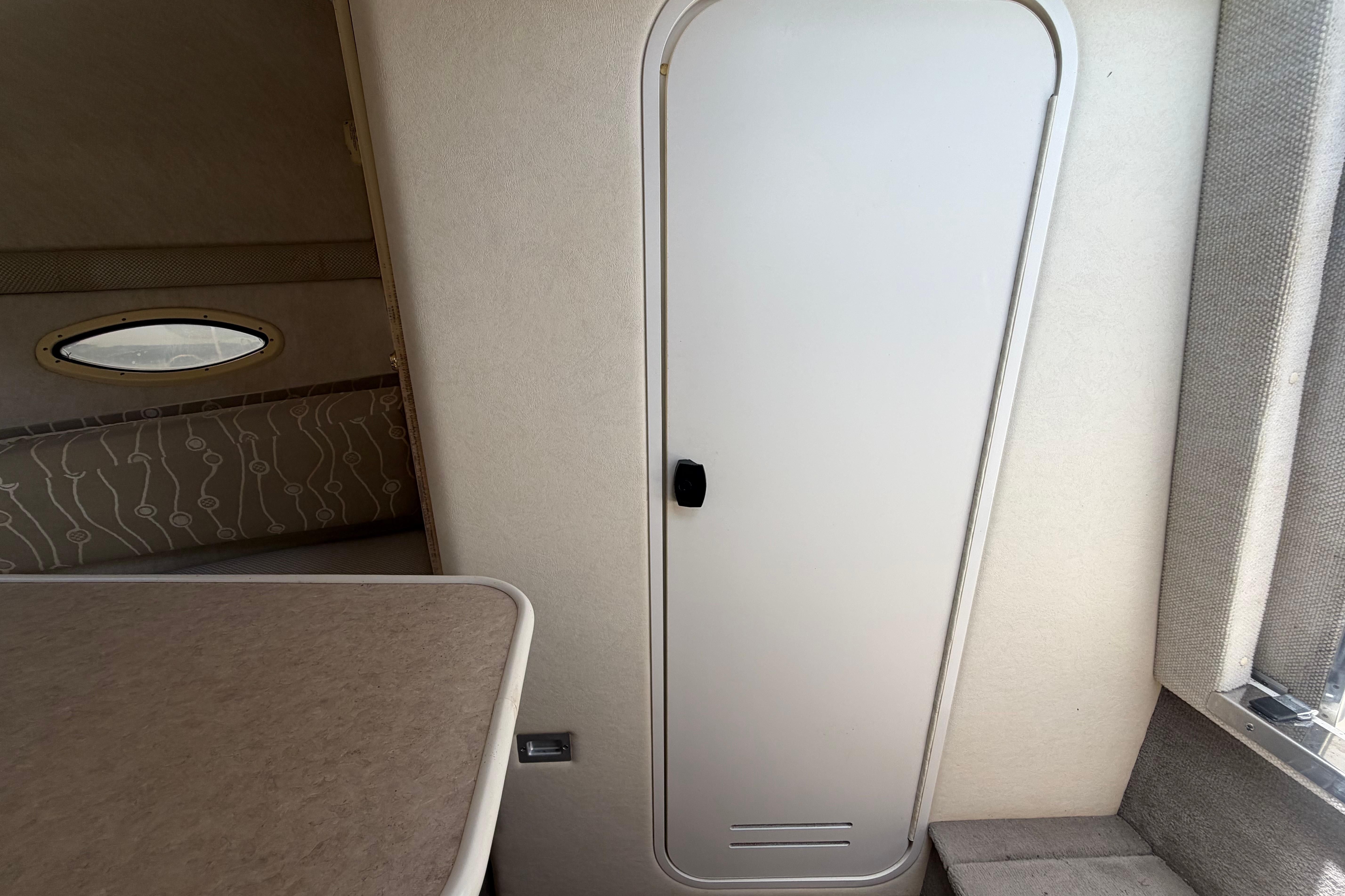 Interior cabin view of 2006 Sea Ray 250 Amberjack boat, featuring a closed door and seating area.