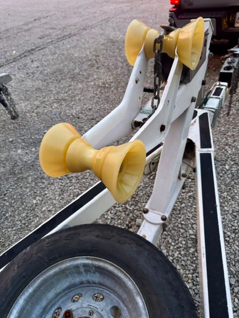 Boat trailer with yellow rollers and chain.