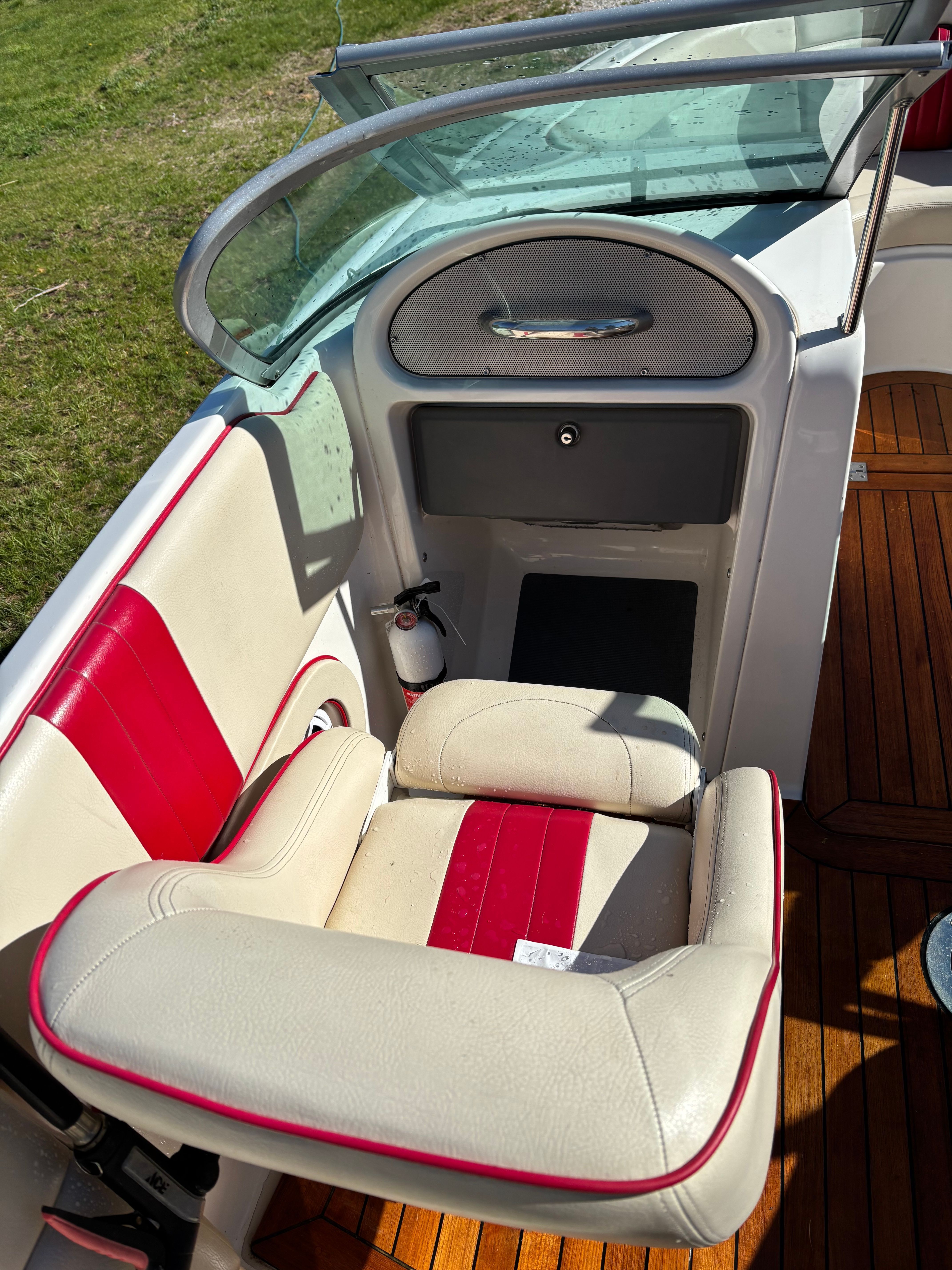 A seating area with cream and red upholstery on a boat with wooden flooring.