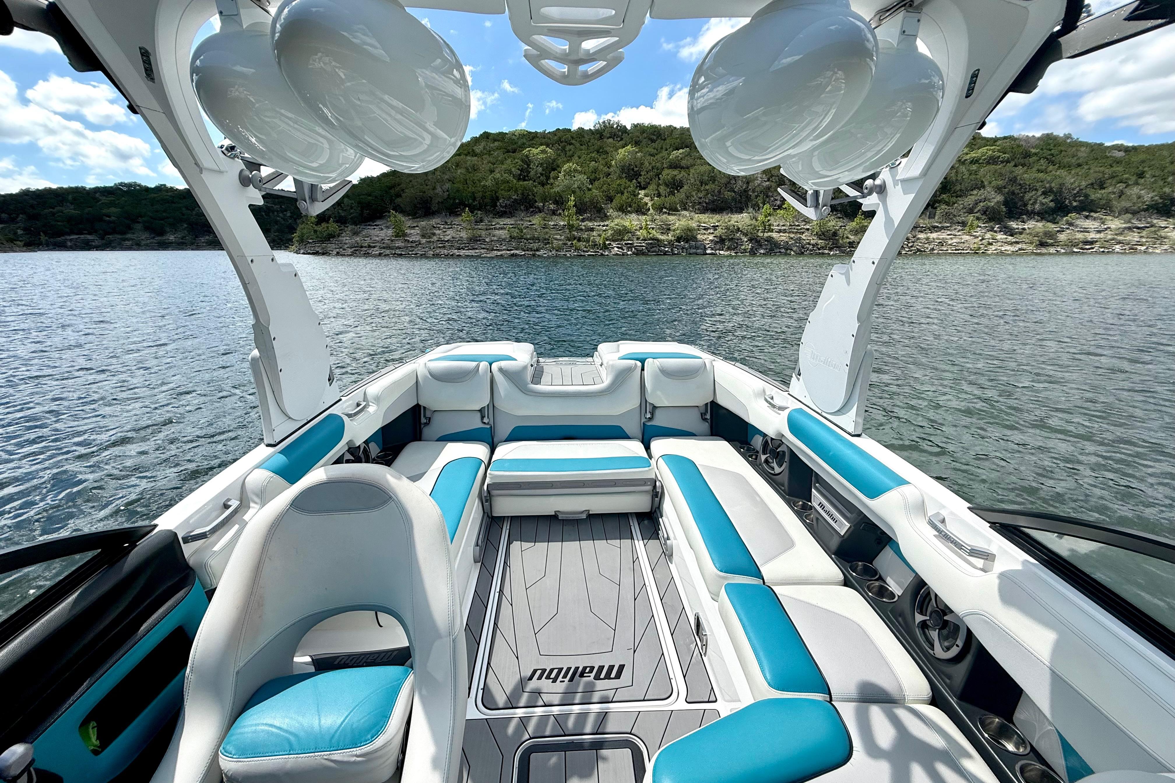 2017 Malibu M235 boat interior with blue and white seating on a scenic lake.