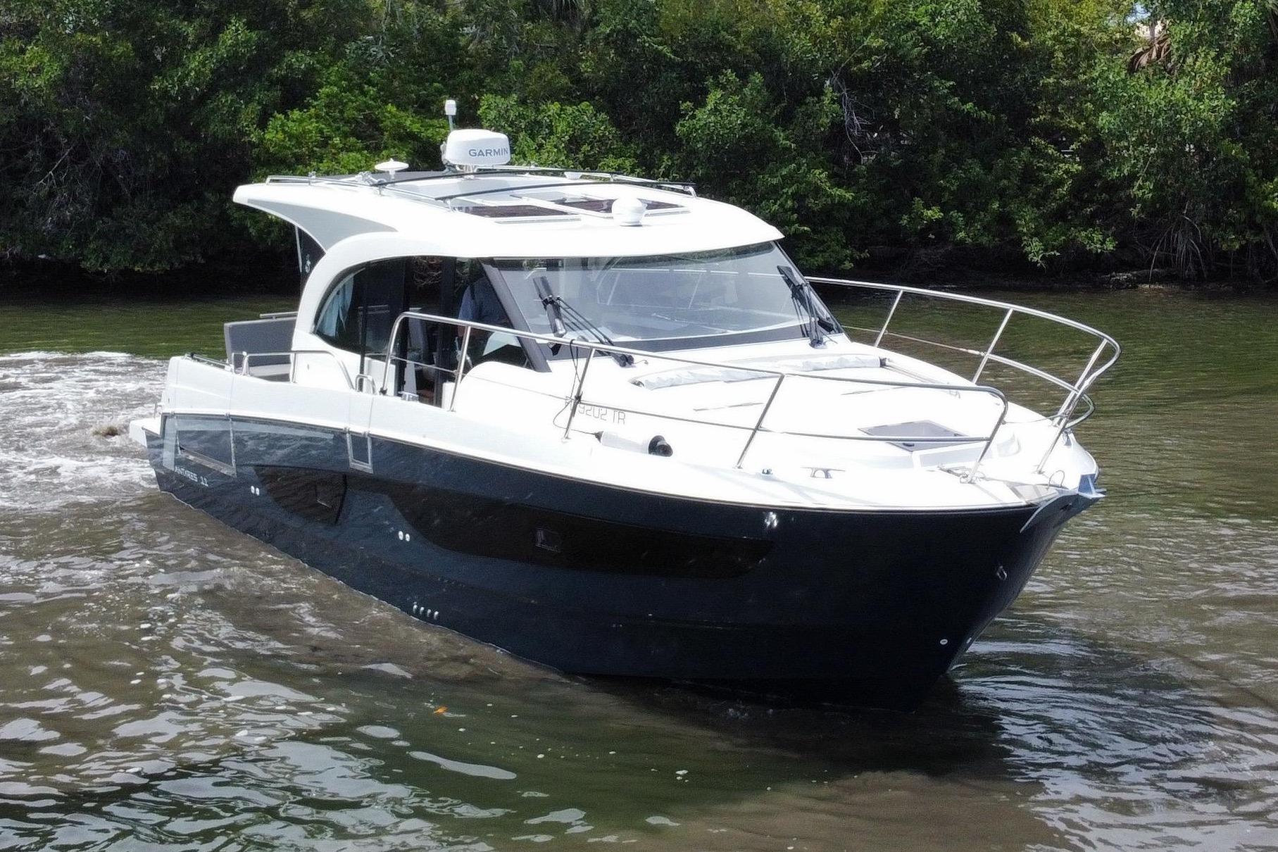The 2024 Beneteau Antares 11 cruises on a calm river, surrounded by lush greenery.