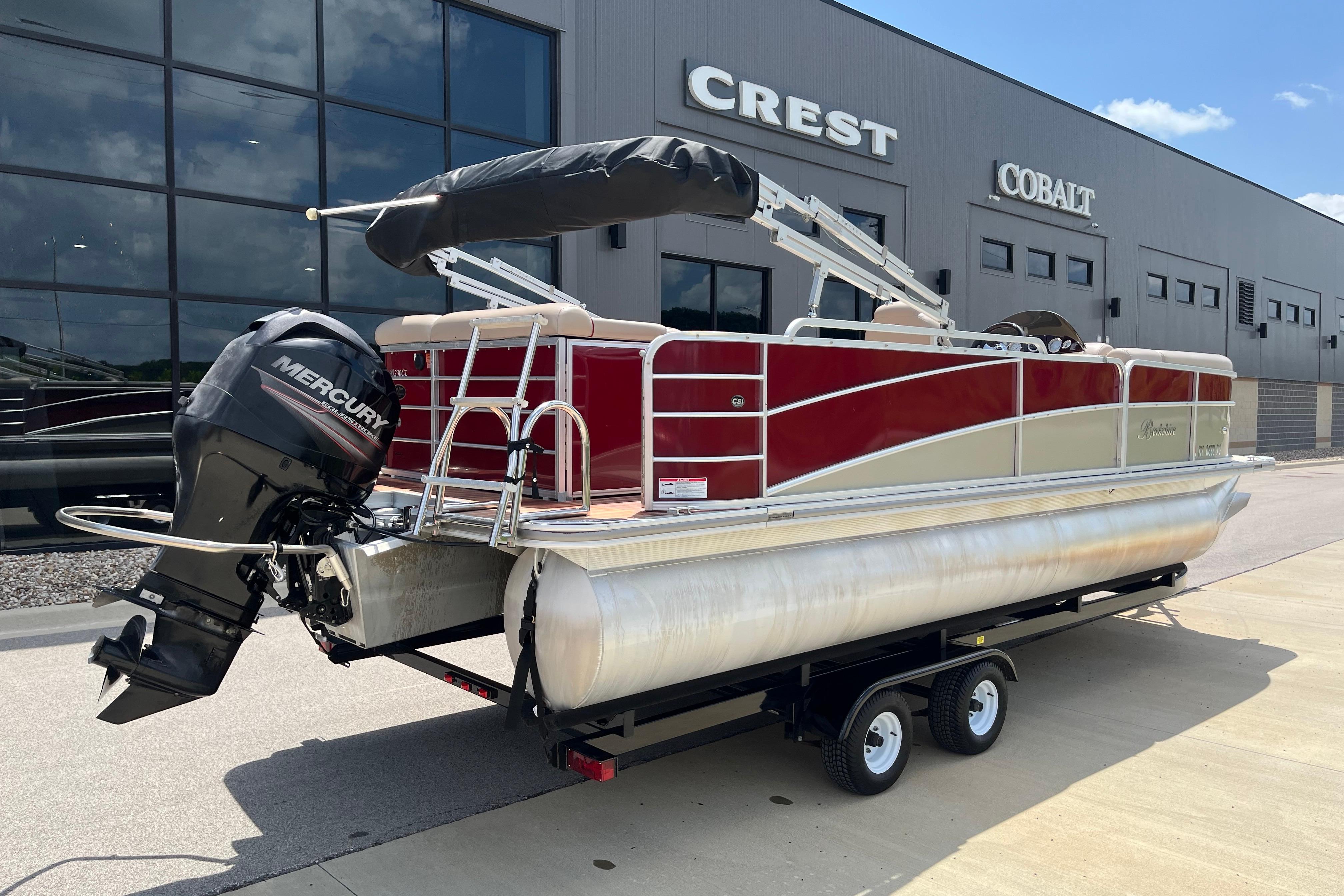 2013 Berkshire 230CL CTS pontoon boat with Mercury engine on trailer, outside dealership.