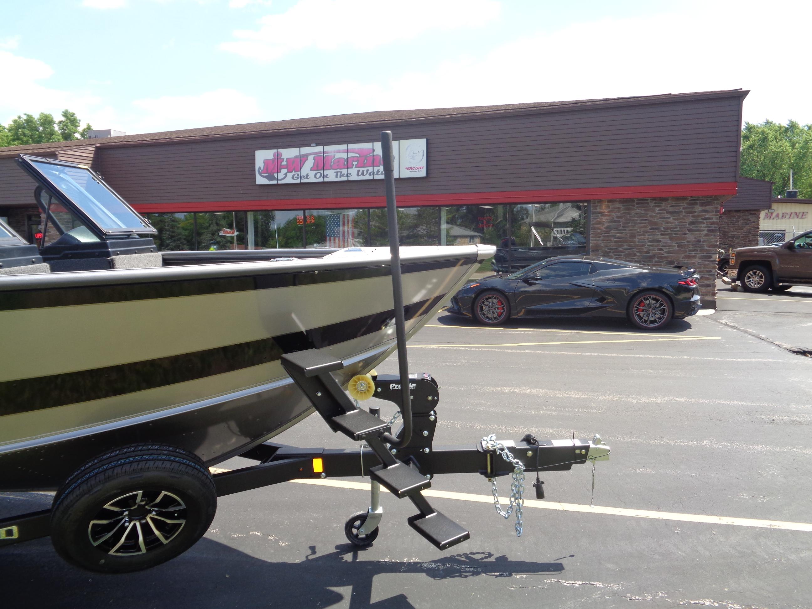 2025 Lund 2075 Fisherman boat on trailer in parking lot near sports car.