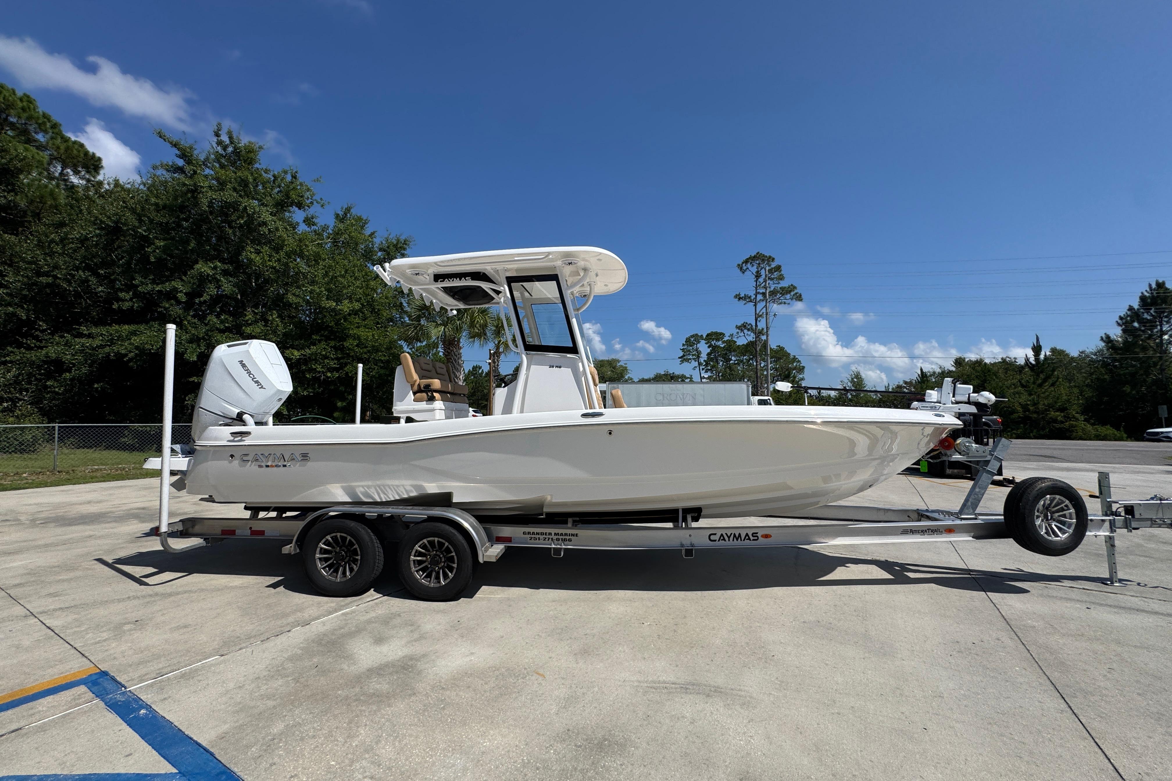 2027 Caymas 26 HB boat on trailer, parked outdoors under clear blue sky.