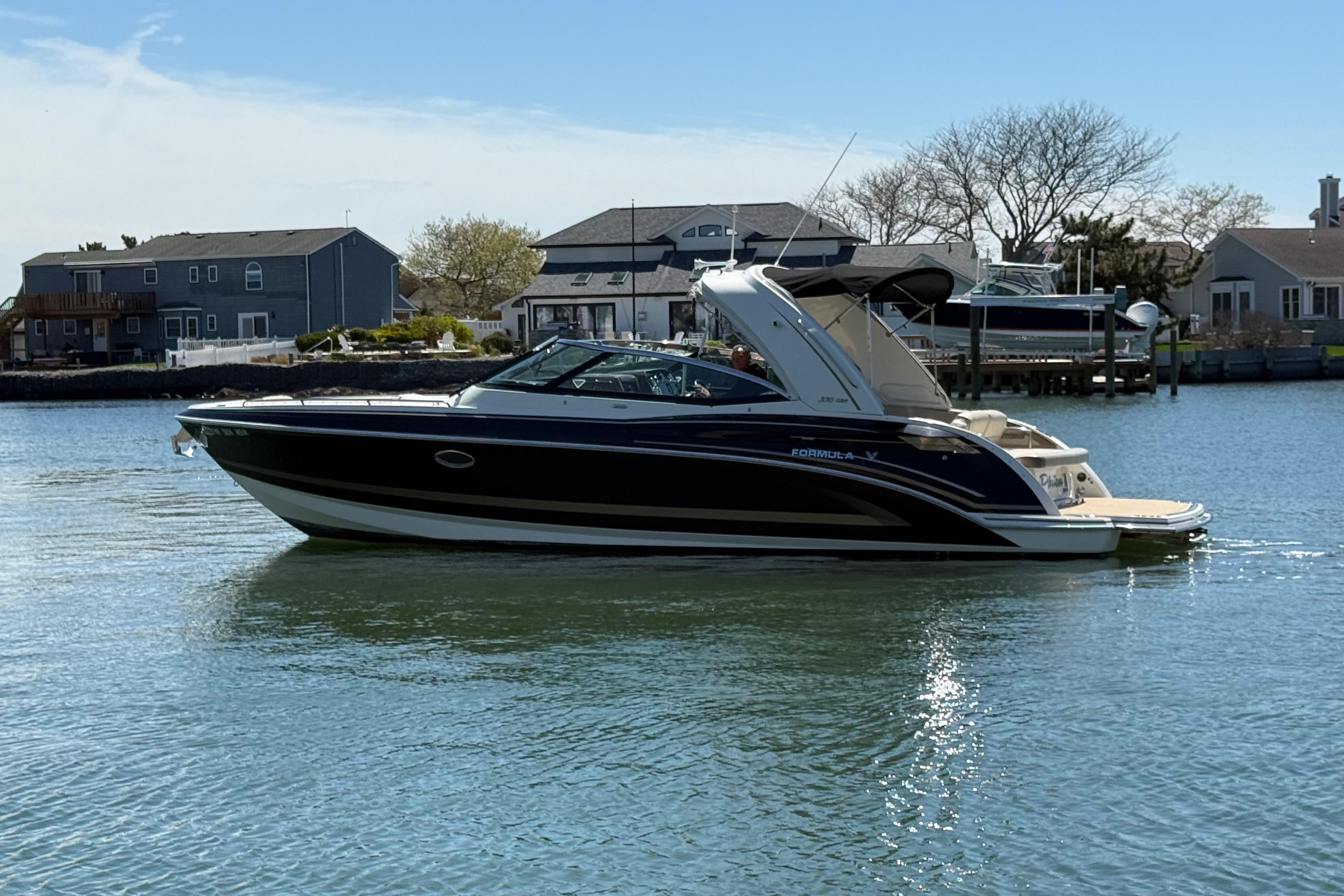 2015 Formula 330 Crossover Bowrider on calm water near residential docks.