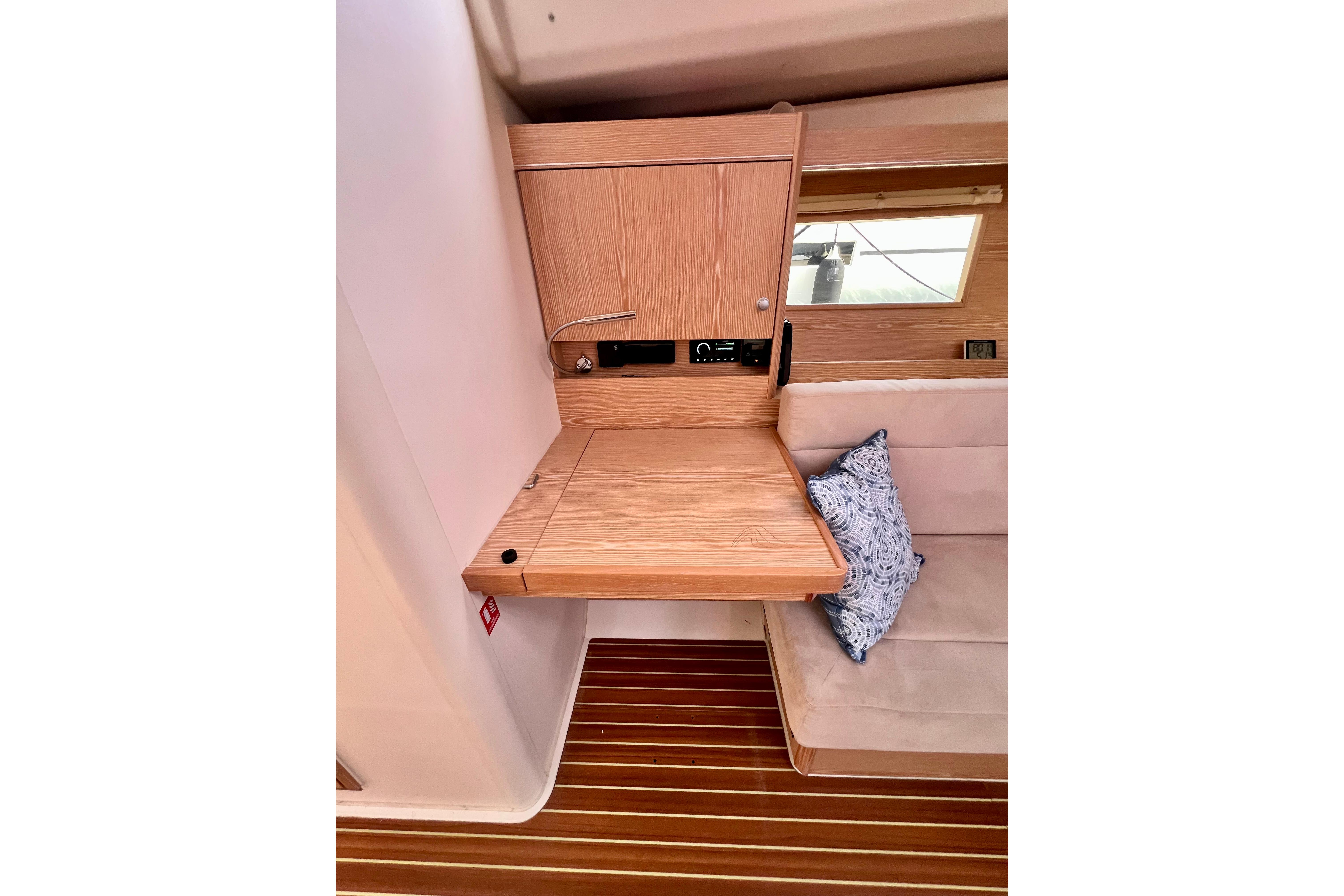 Interior of 2016 Hanse 455 yacht with wooden desk and cushioned seating.