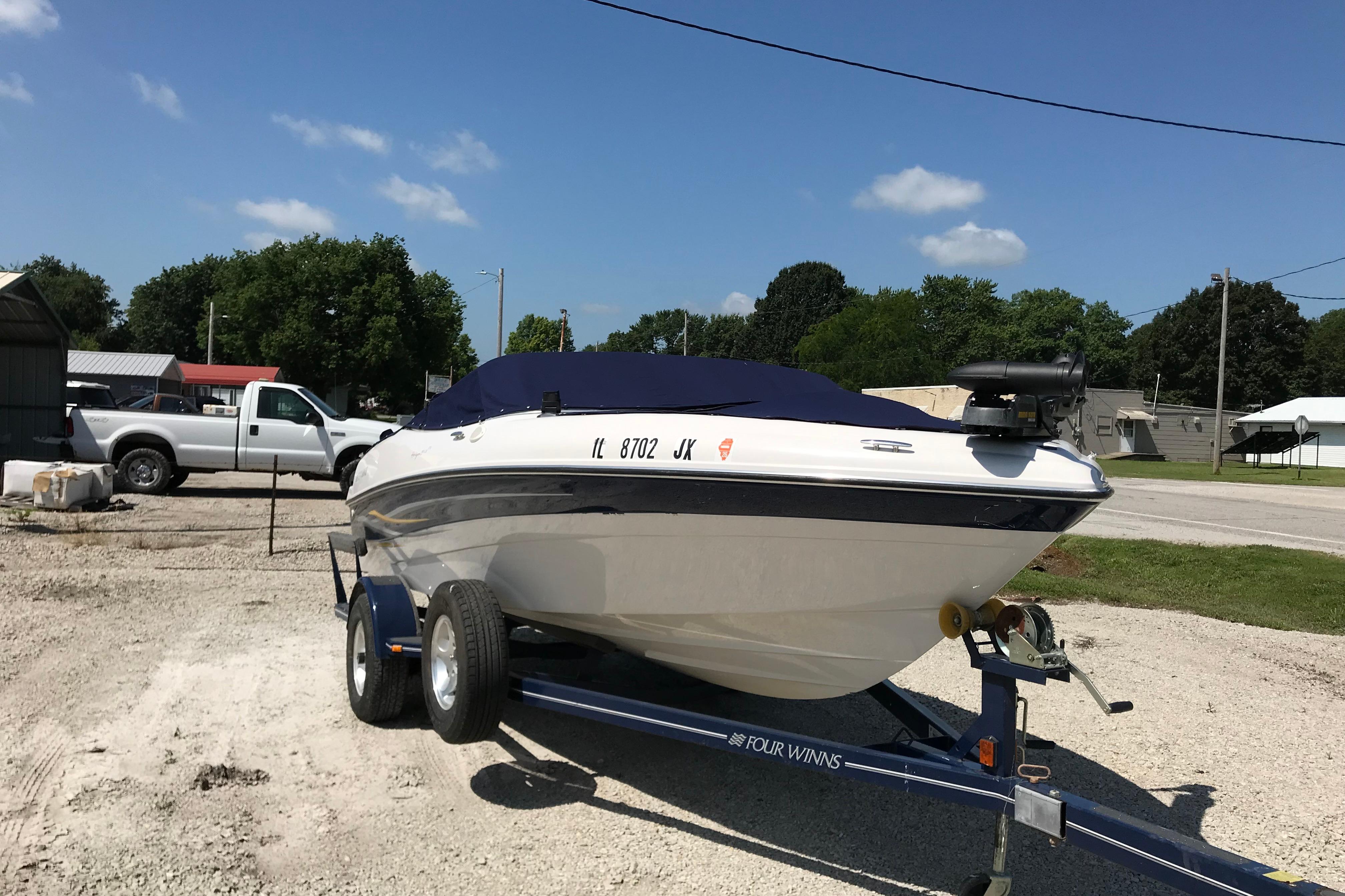 2005 Four Winns 180 Horizon FS boat on trailer, parked outdoors under clear sky.