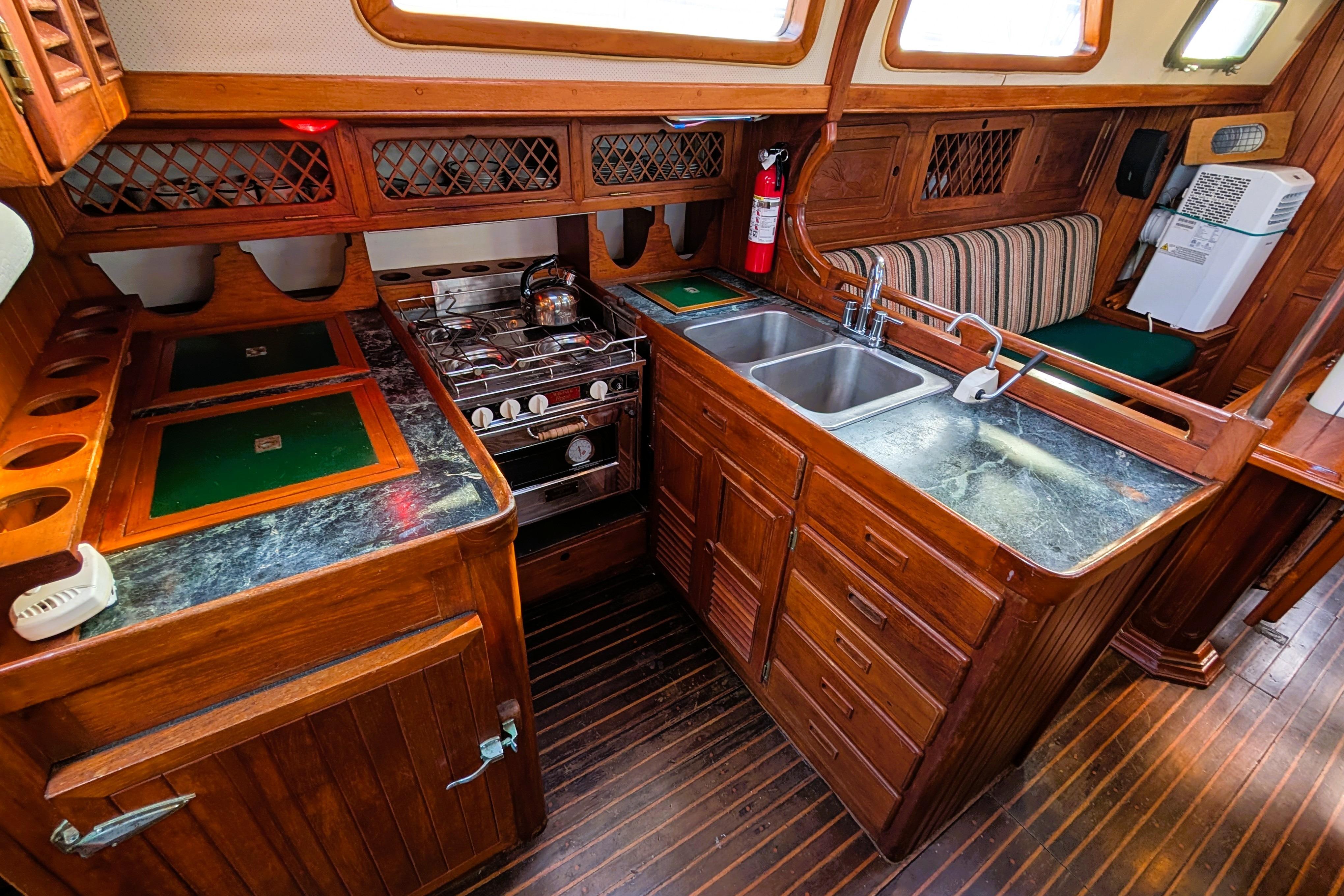 Vintage 1983 Perry 41 yacht kitchen with wood cabinetry, stove, and dual sink.