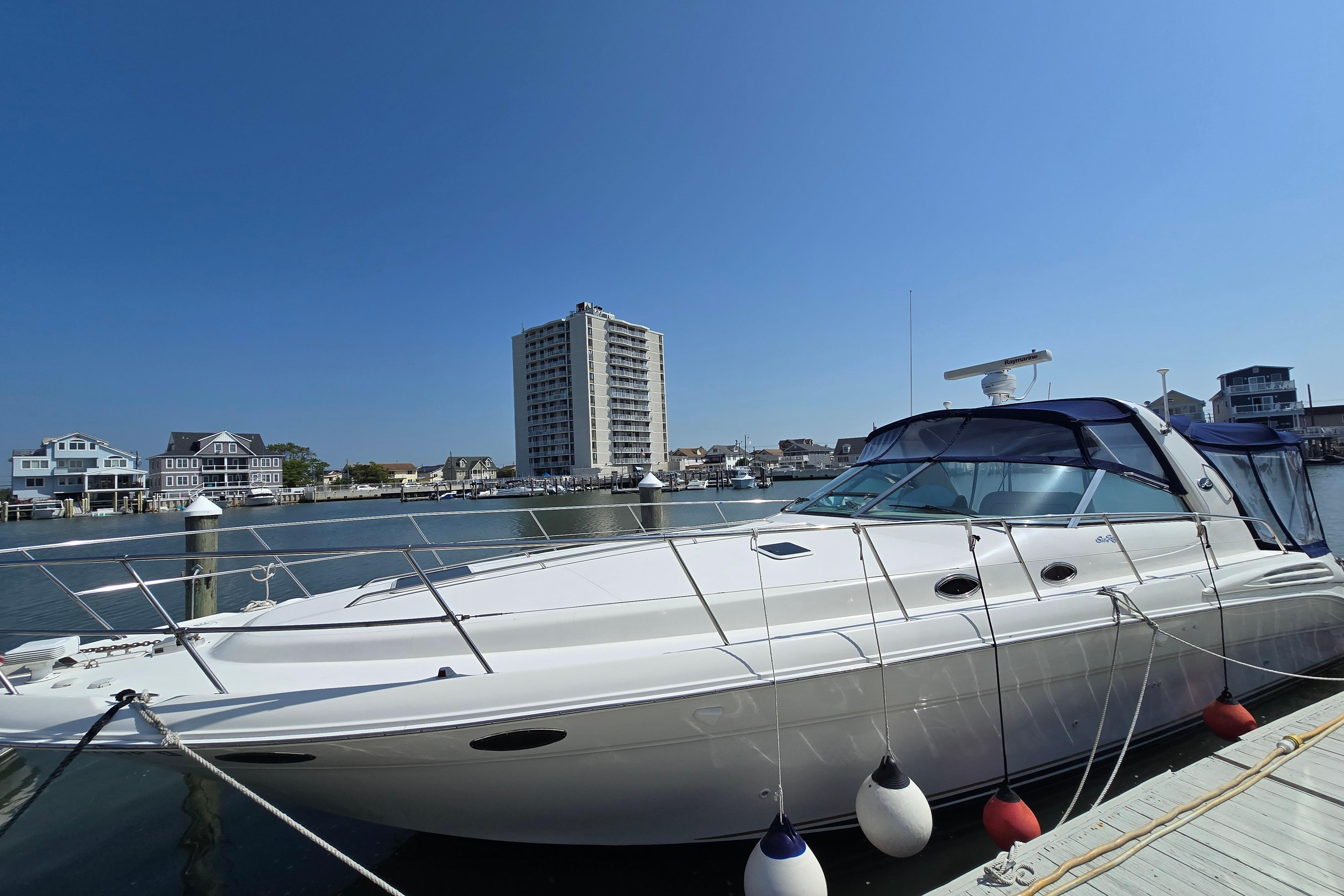 1999 Sea Ray Sundancer 400 yacht docked in a marina with waterfront buildings in the background.