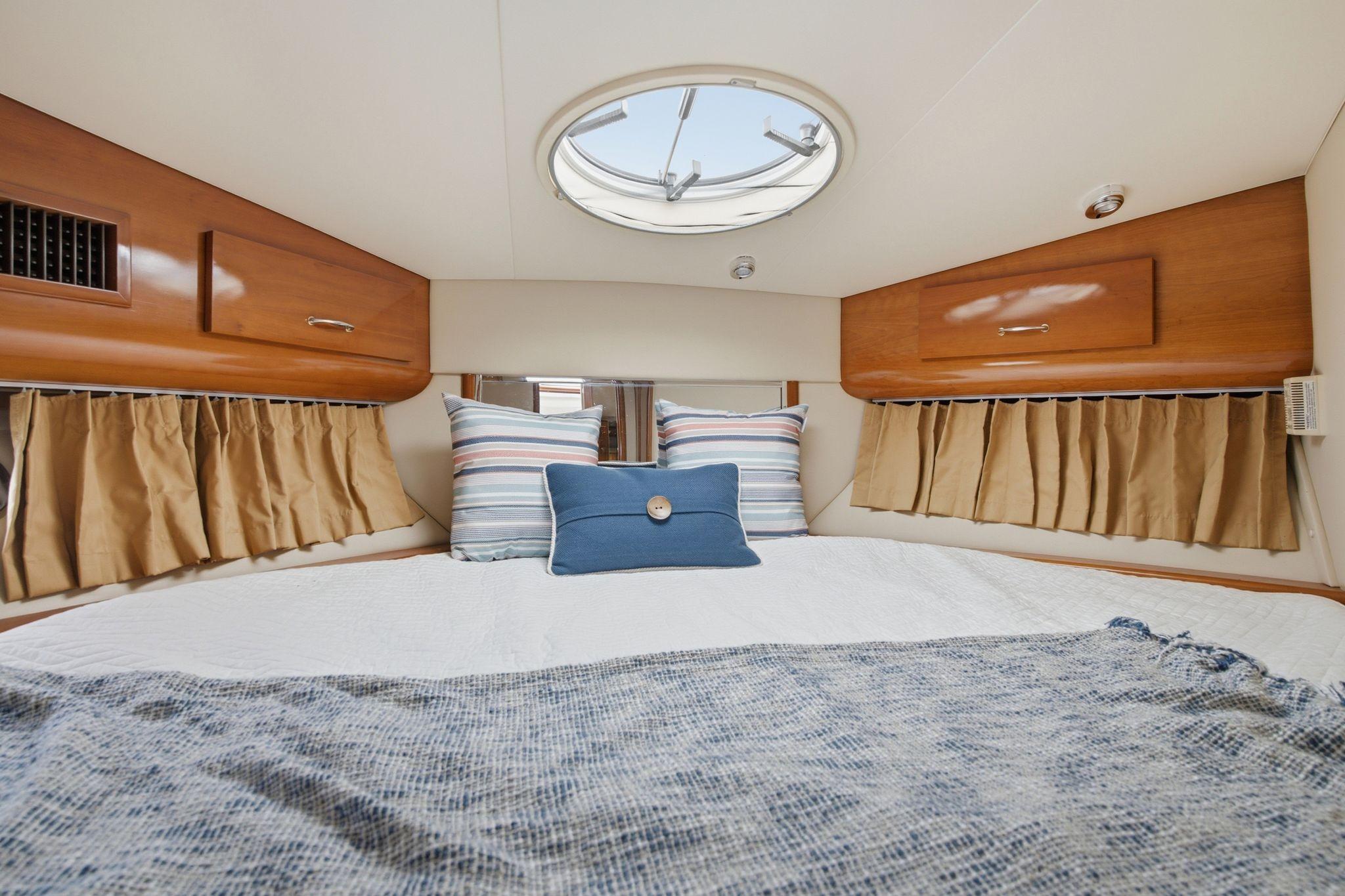 Cozy bedroom interior of 2005 Carver 39 Motor Yacht with skylight and striped pillows.