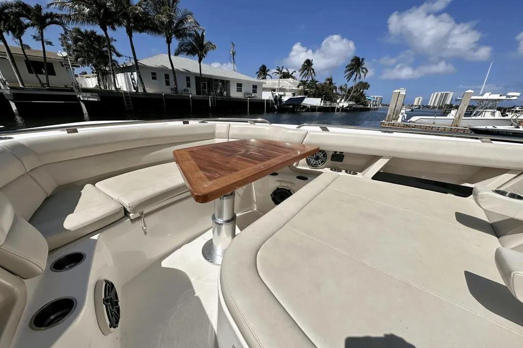 2019 Boston Whaler 350 Realm boat interior with seating and wooden table, docked by waterfront homes.