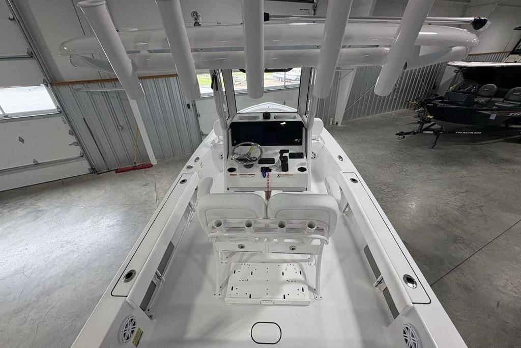2026 Sportsman Masters 227 boat interior with helm, seats, and rod holders in a garage.