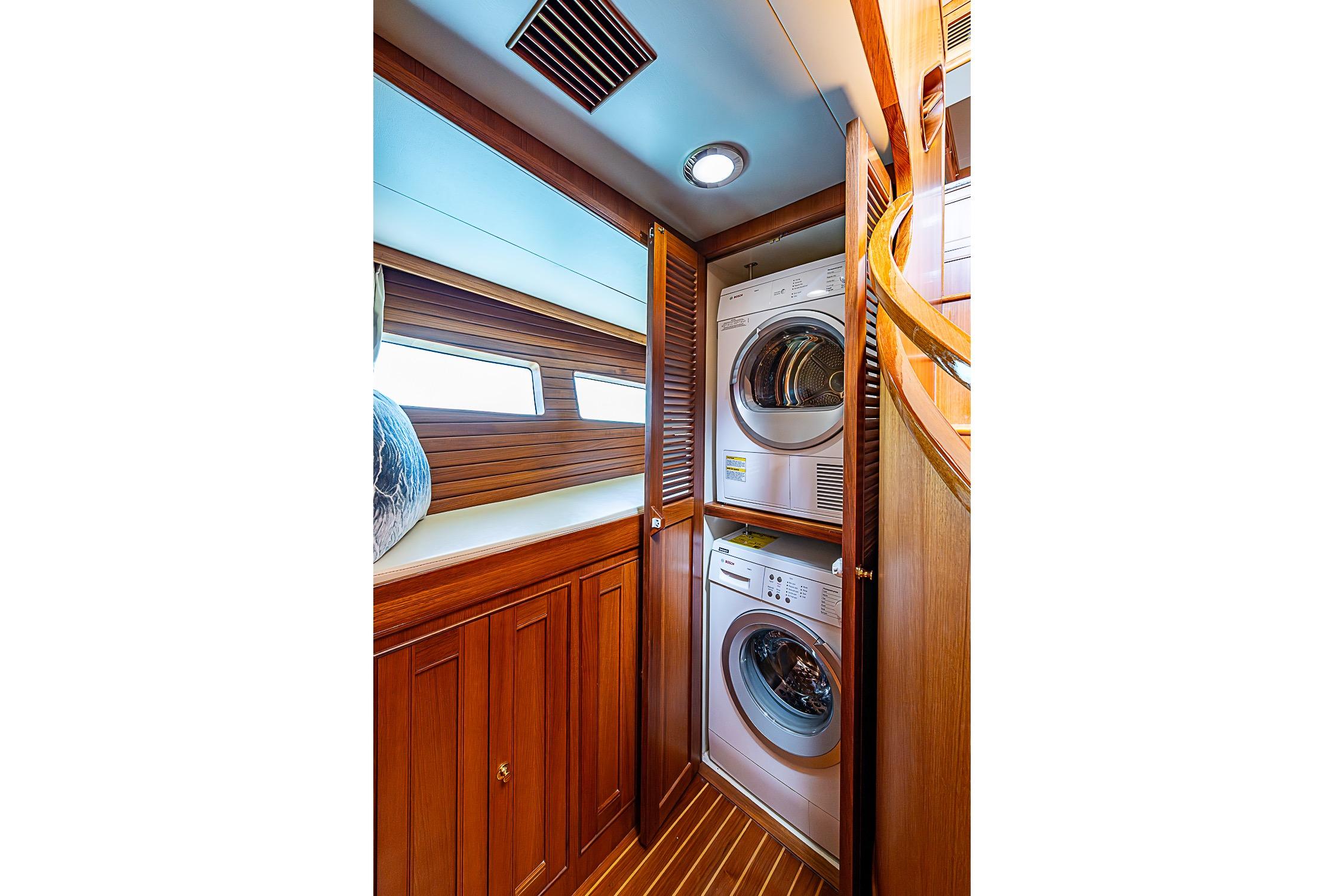 Laundry area with stacked washer and dryer in 2014 Marlow 80 Explorer yacht.