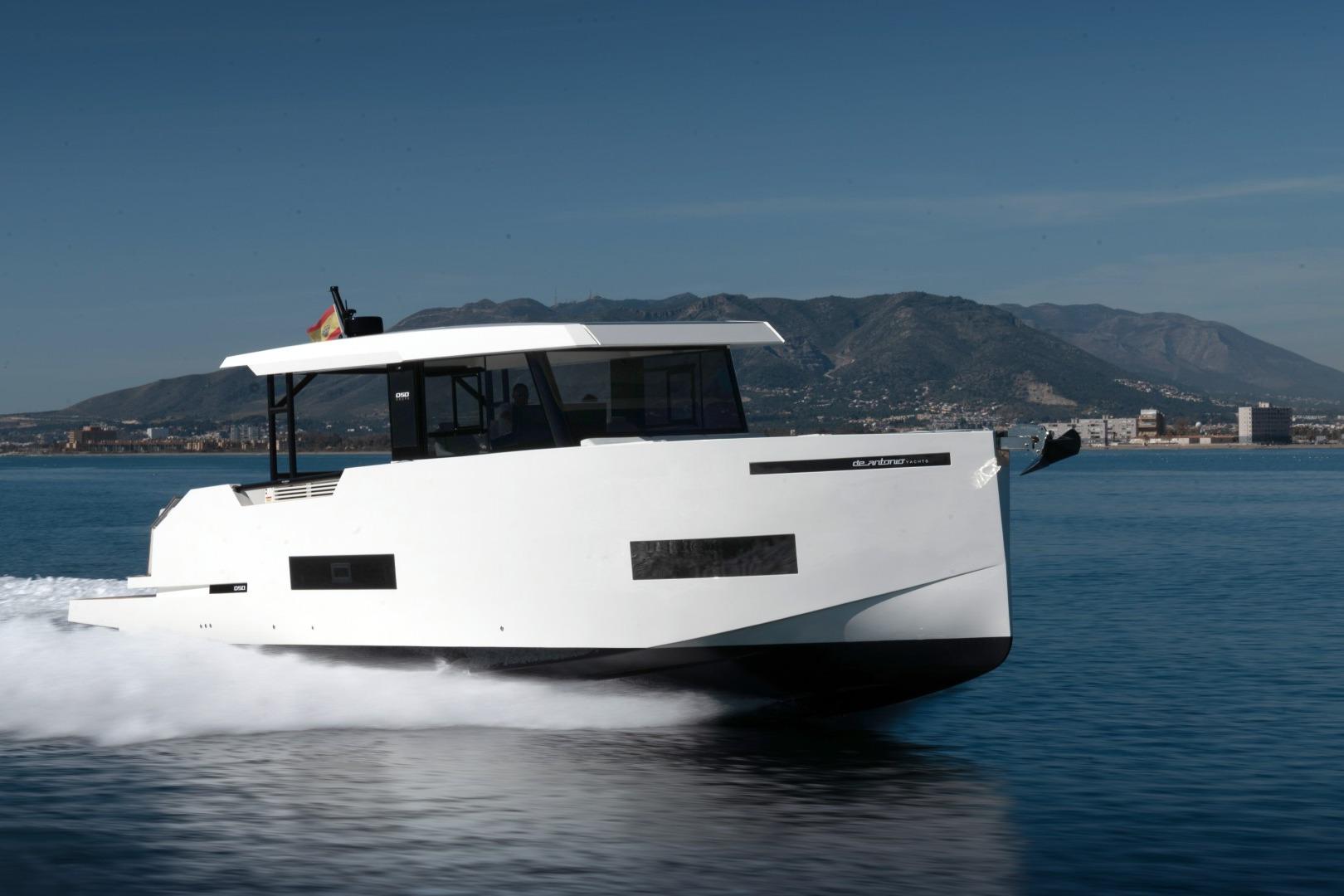 2026 De Antonio Yachts 50 Coupe cruising on calm waters with mountainous backdrop.