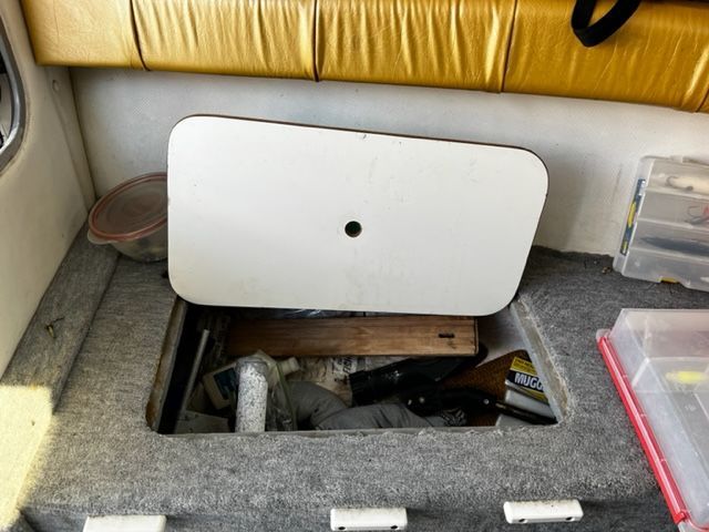 An open storage compartment on a boat with various items inside.