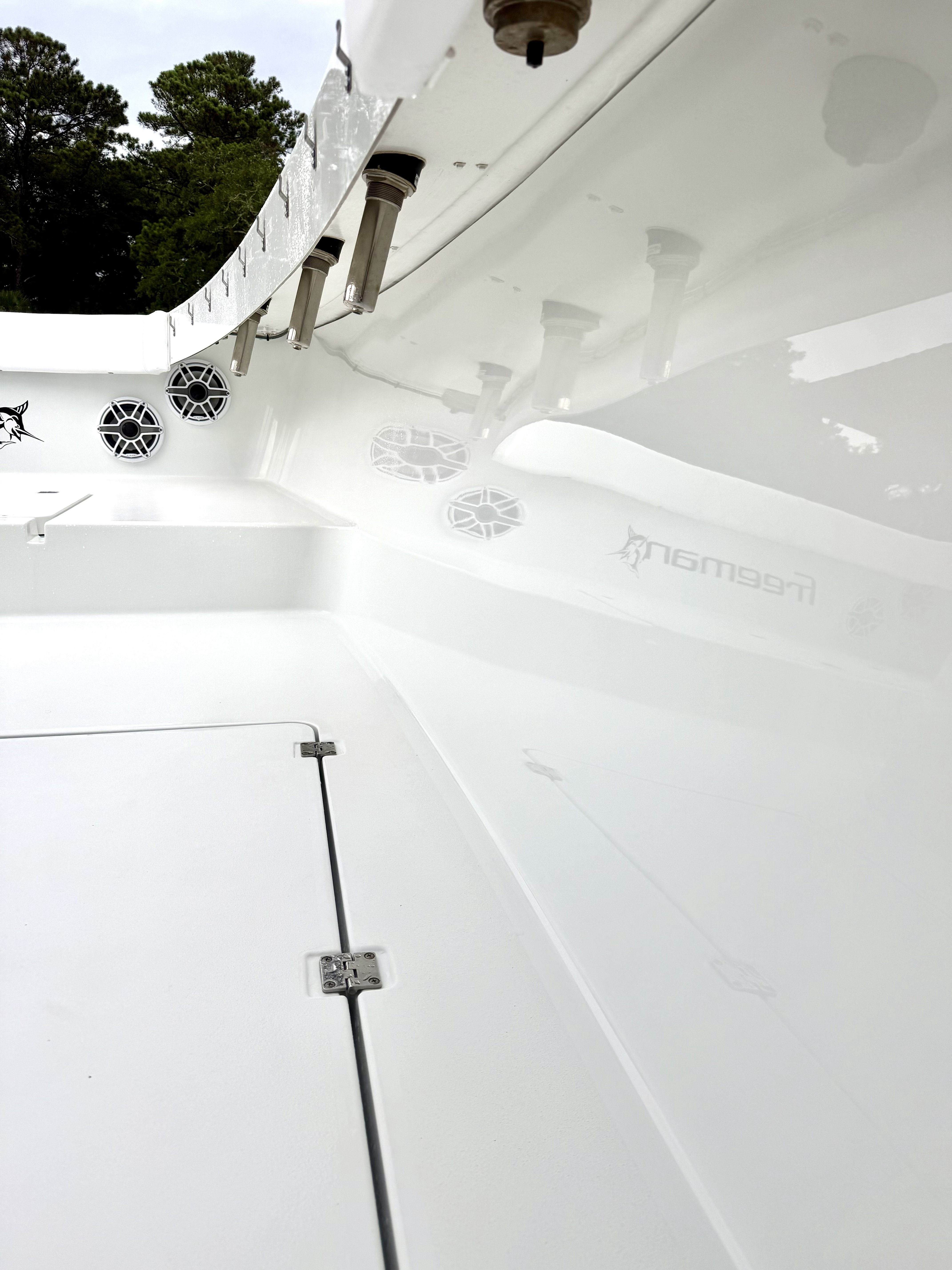 The image shows the deck of a 2018 Freeman 34VH boat with speakers and fishing rod holders.