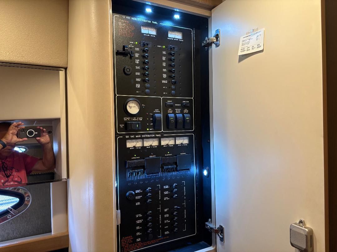 Electrical control panel in a yacht with various switches and gauges, illuminated by LED lights.