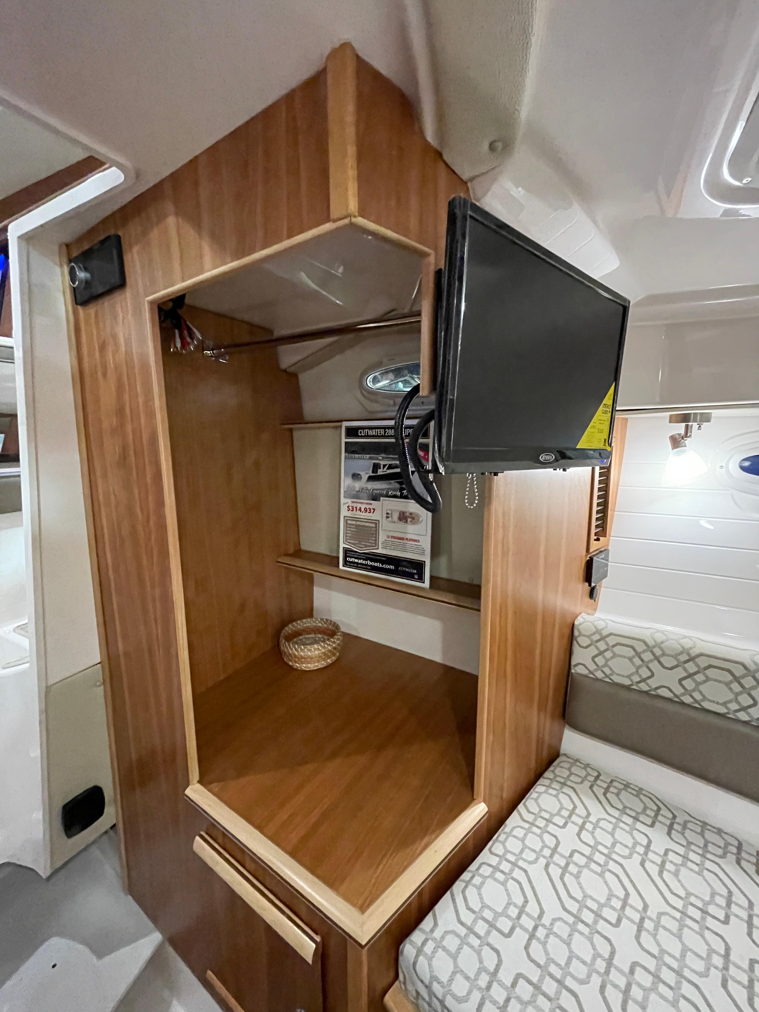 Interior of 2026 Cutwater C-288 Coupe with wooden cabinetry and mounted TV.