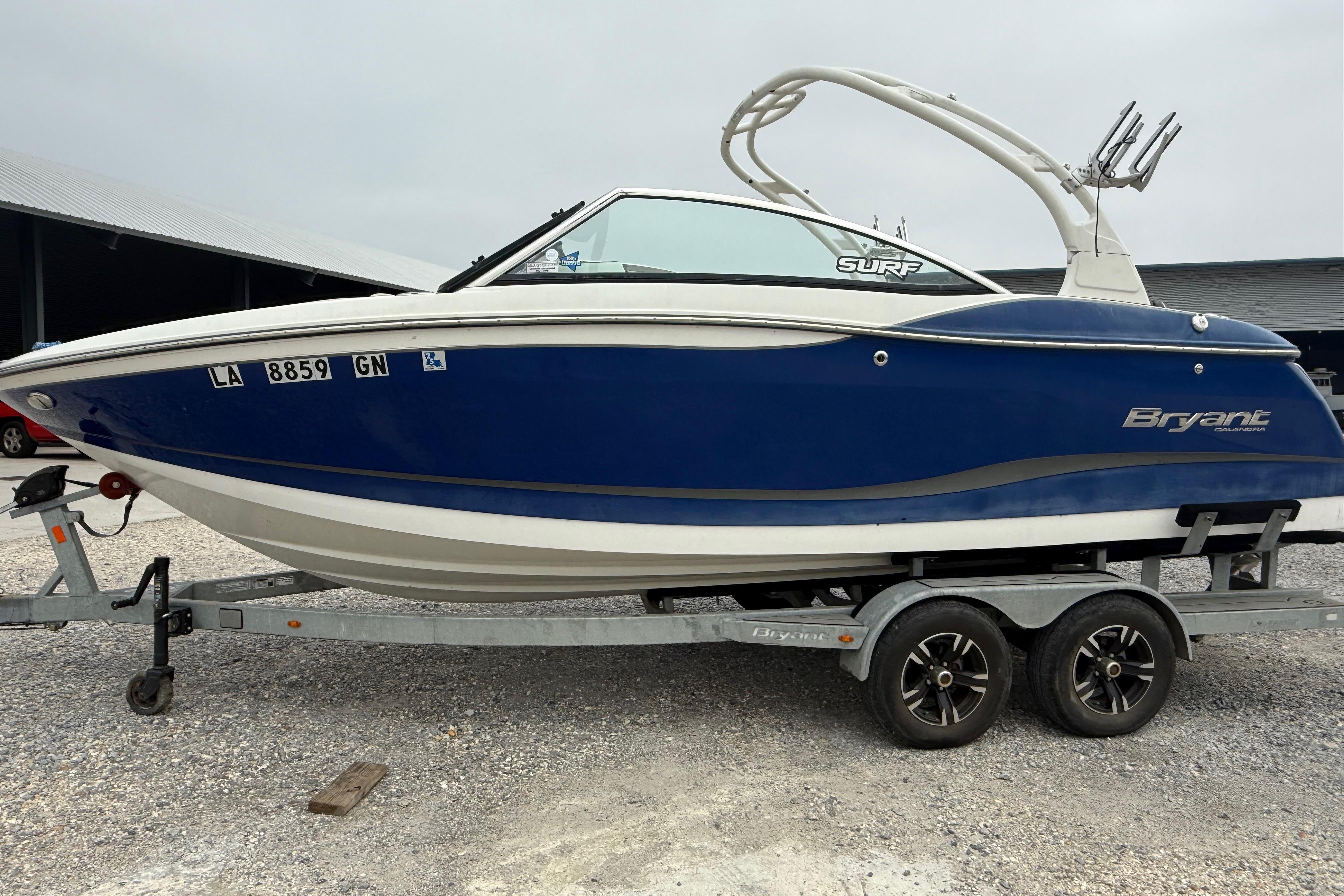 2018 Bryant Calandra boat on trailer, blue and white design, parked outdoors.