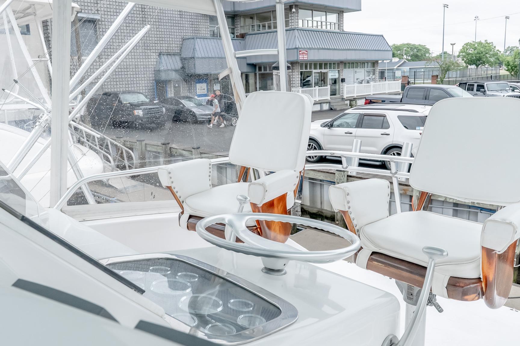 Helm of 2000 Viking 50' Convertible yacht with white captain chairs and steering wheel.