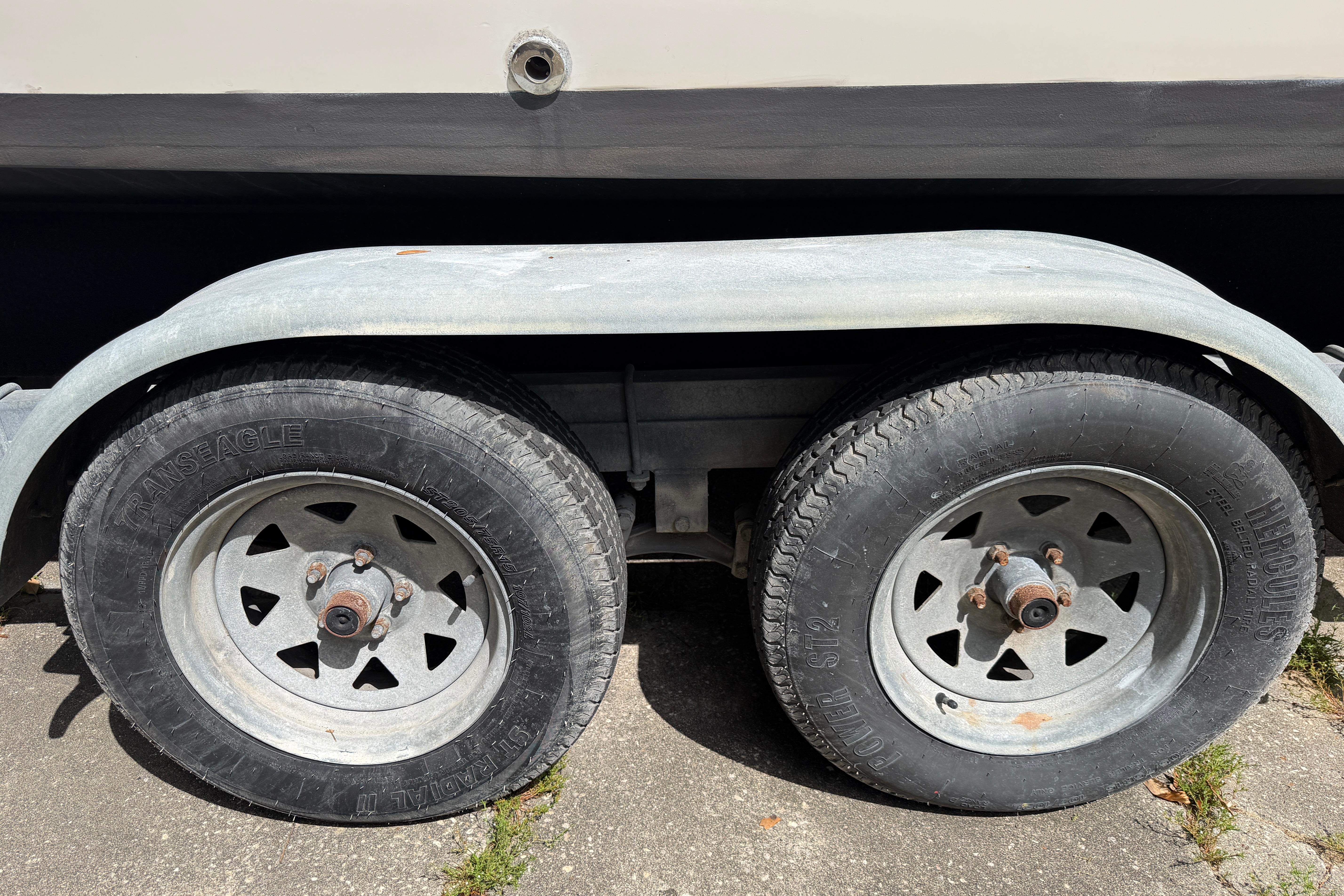 Trailer wheels of a 1987 Grady-White Seafarer 226 boat on pavement.
