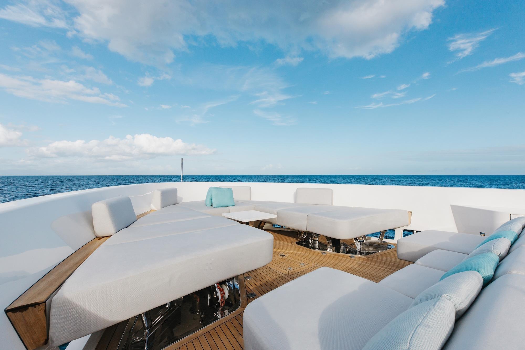 Luxurious Sanlorenzo SLA120A yacht deck with modern seating, ocean view, and blue sky, 2020 model.