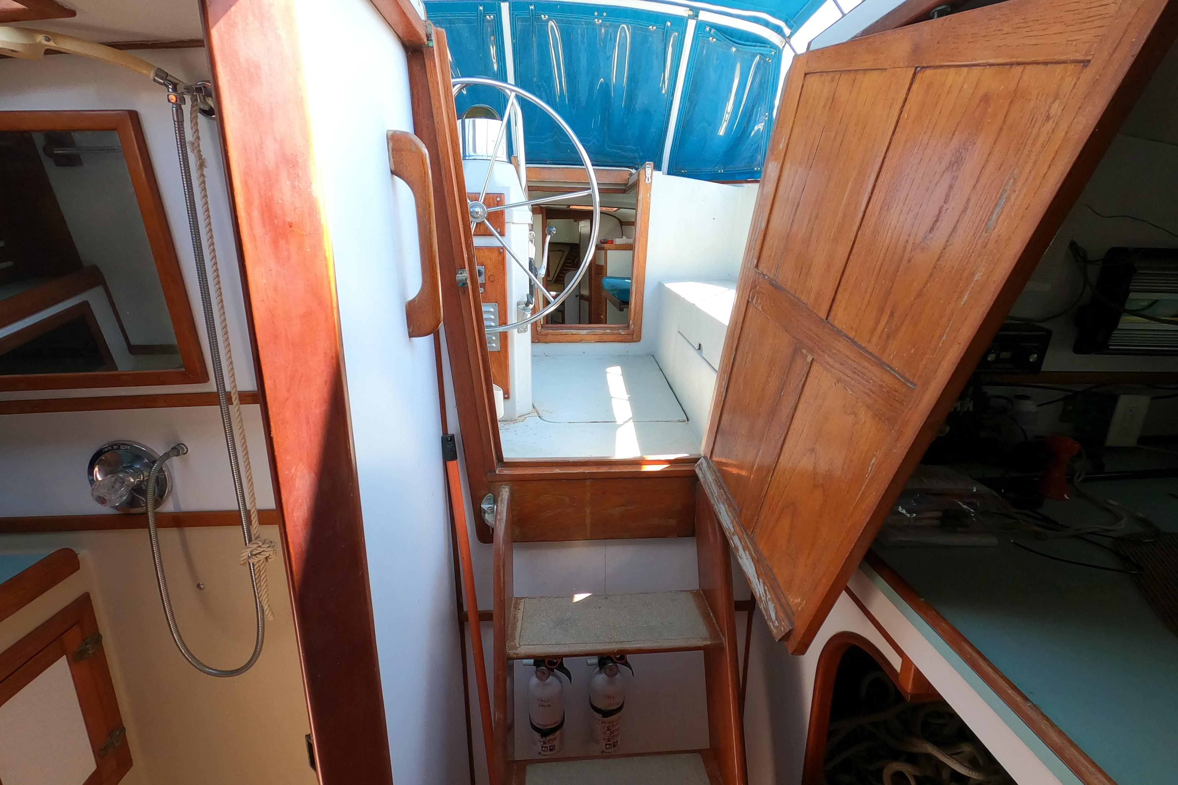 Interior view of a 1978 CSY 44 sailboat, featuring wooden cabinetry and a steering wheel.