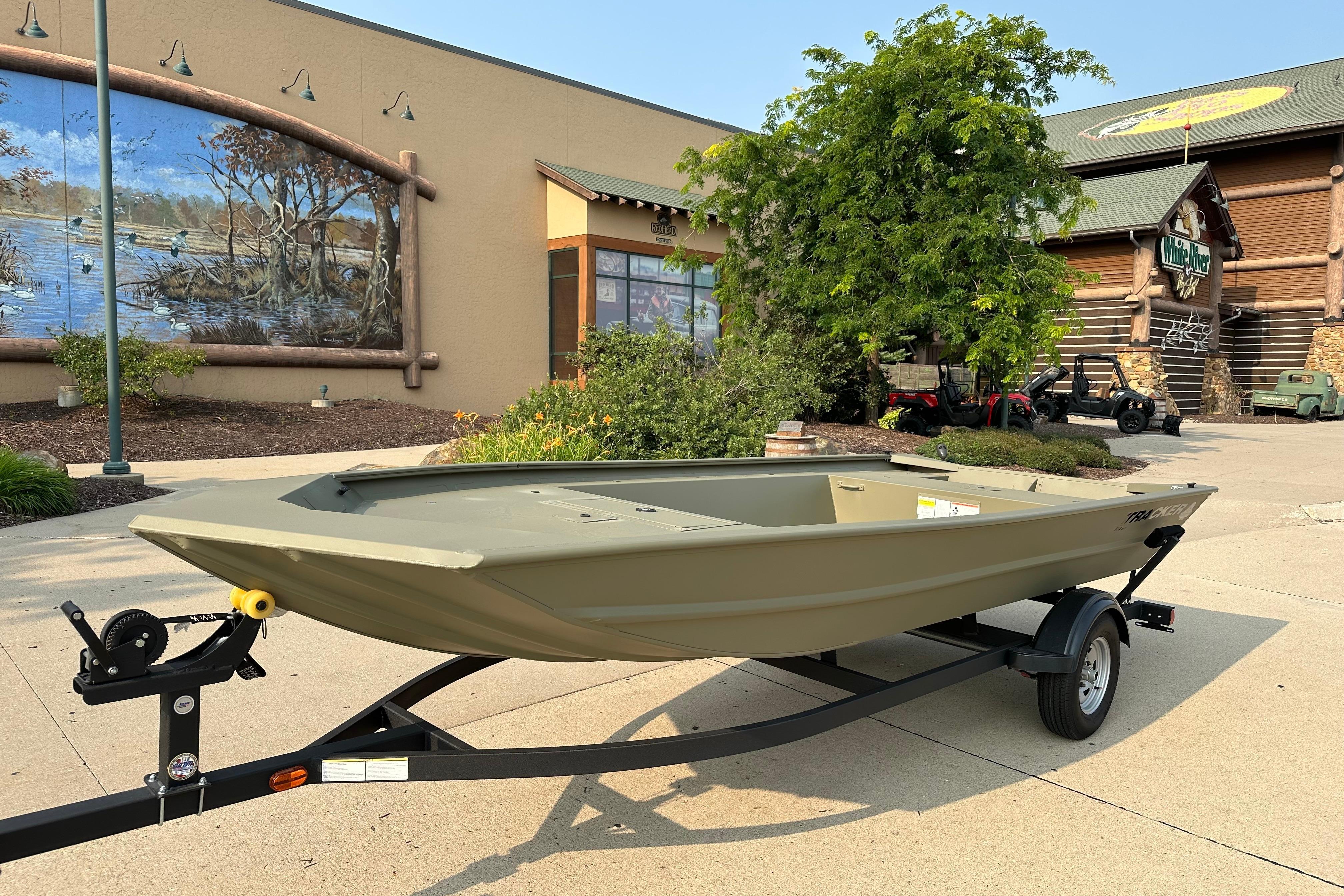 2026 Tracker Grizzly 1754 Utility boat on trailer outside a store with mural.
