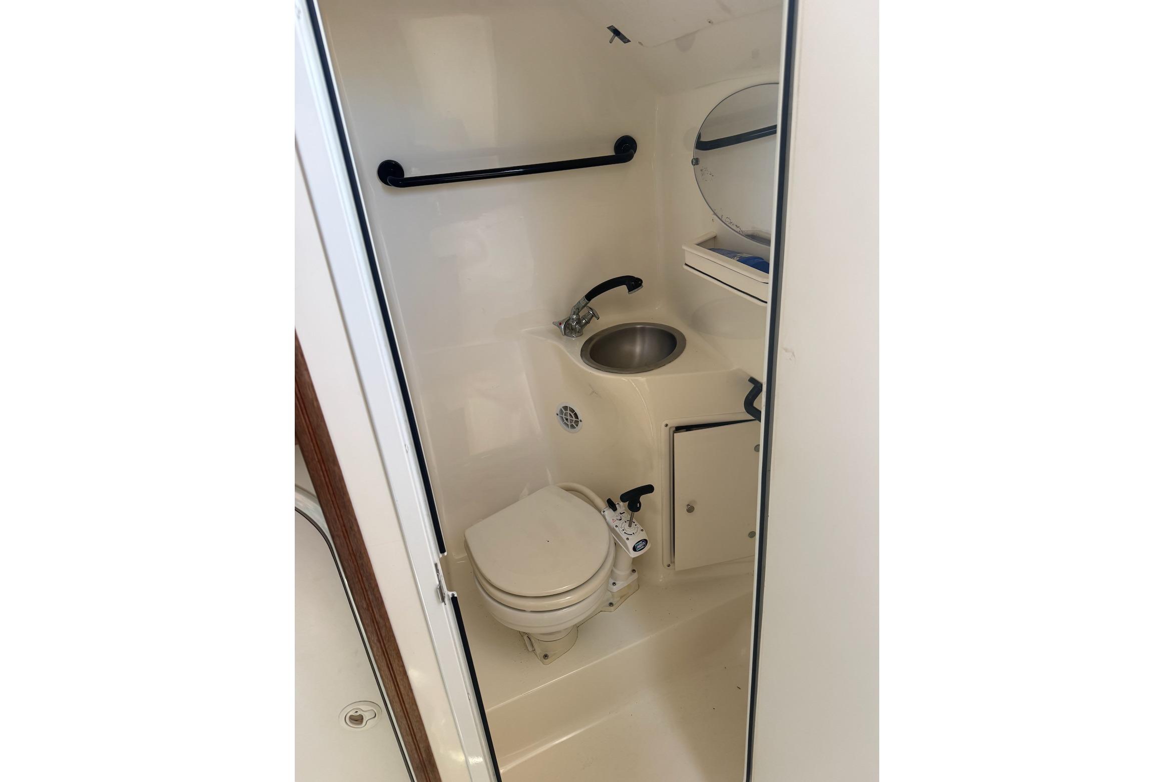 1996 Rinker Fiesta Vee 266 boat bathroom with toilet, sink, and mirror.