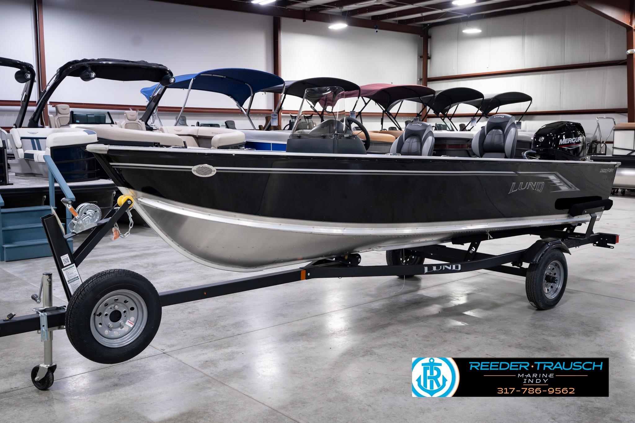 2026 Lund 1600 Fury SS boat on trailer in showroom, featuring sleek black design.