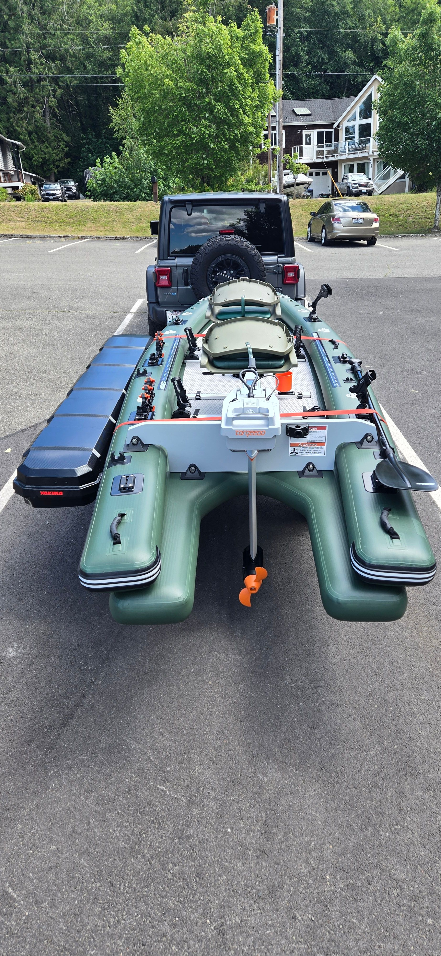 A green inflatable boat with accessories on a trailer, parked in a parking lot.