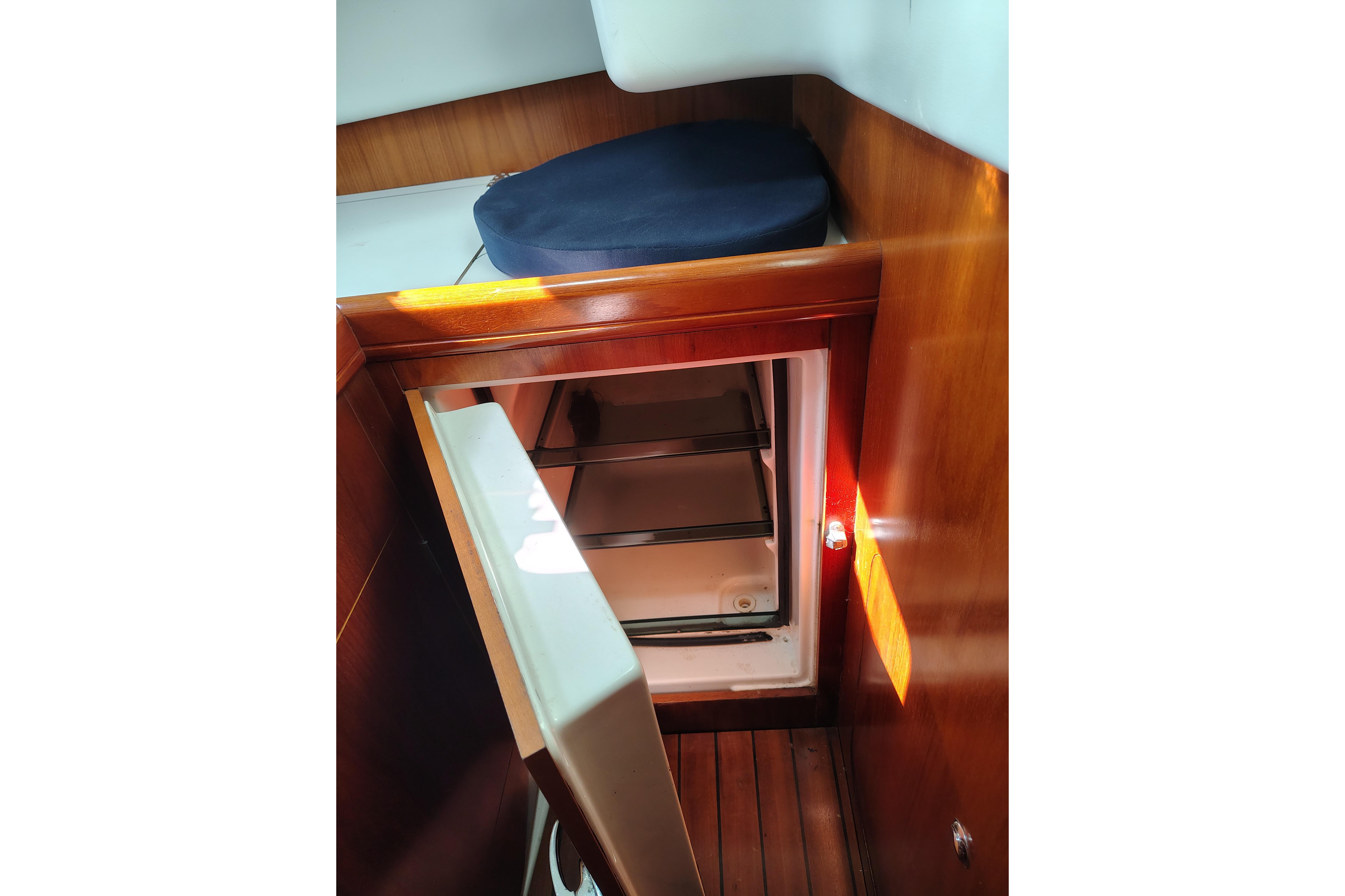 Interior view of a 2001 Beneteau Oceanis 411 sailboat, featuring a compact refrigerator.