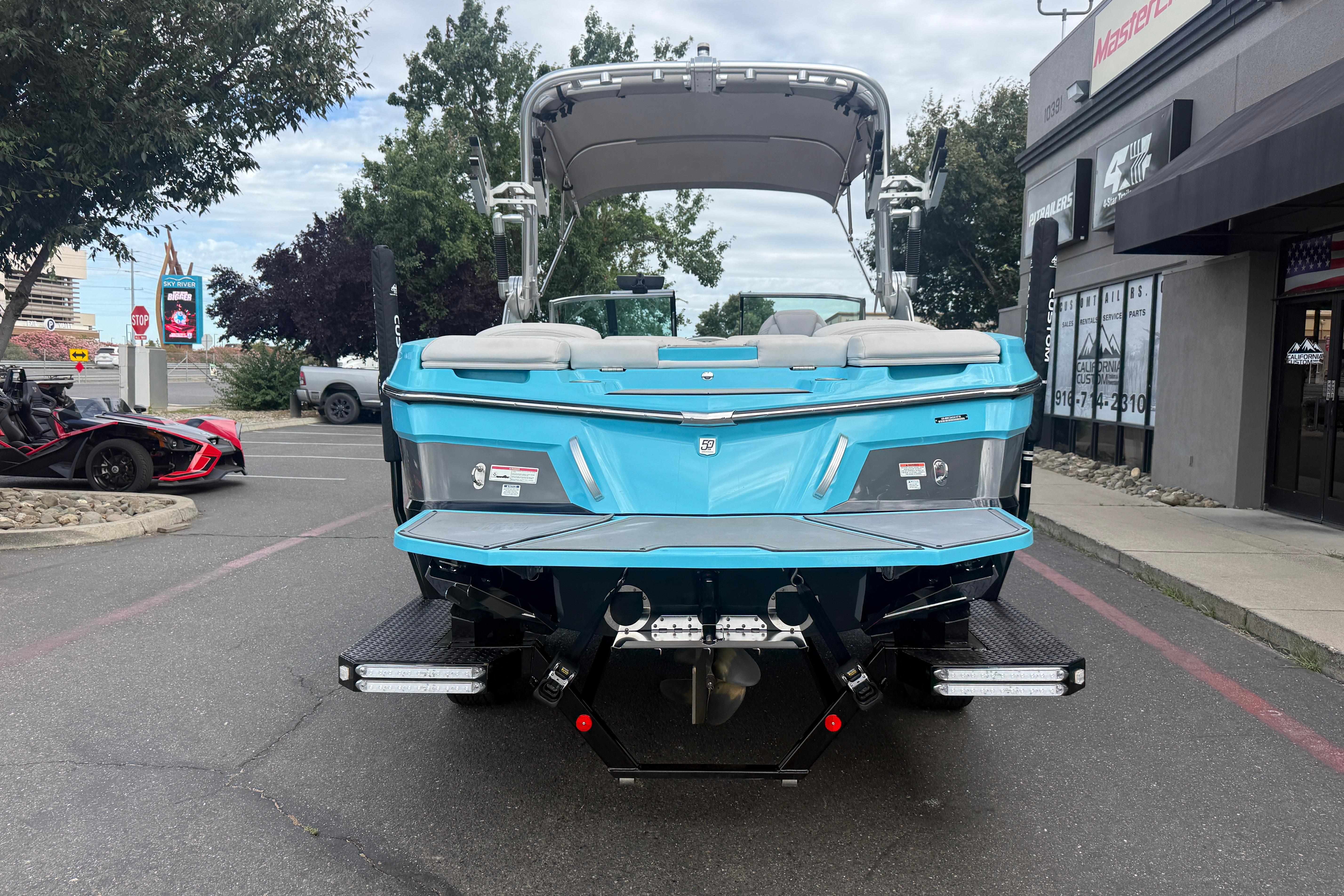2018 MasterCraft XT21 boat in a parking lot, rear view, vibrant blue color.